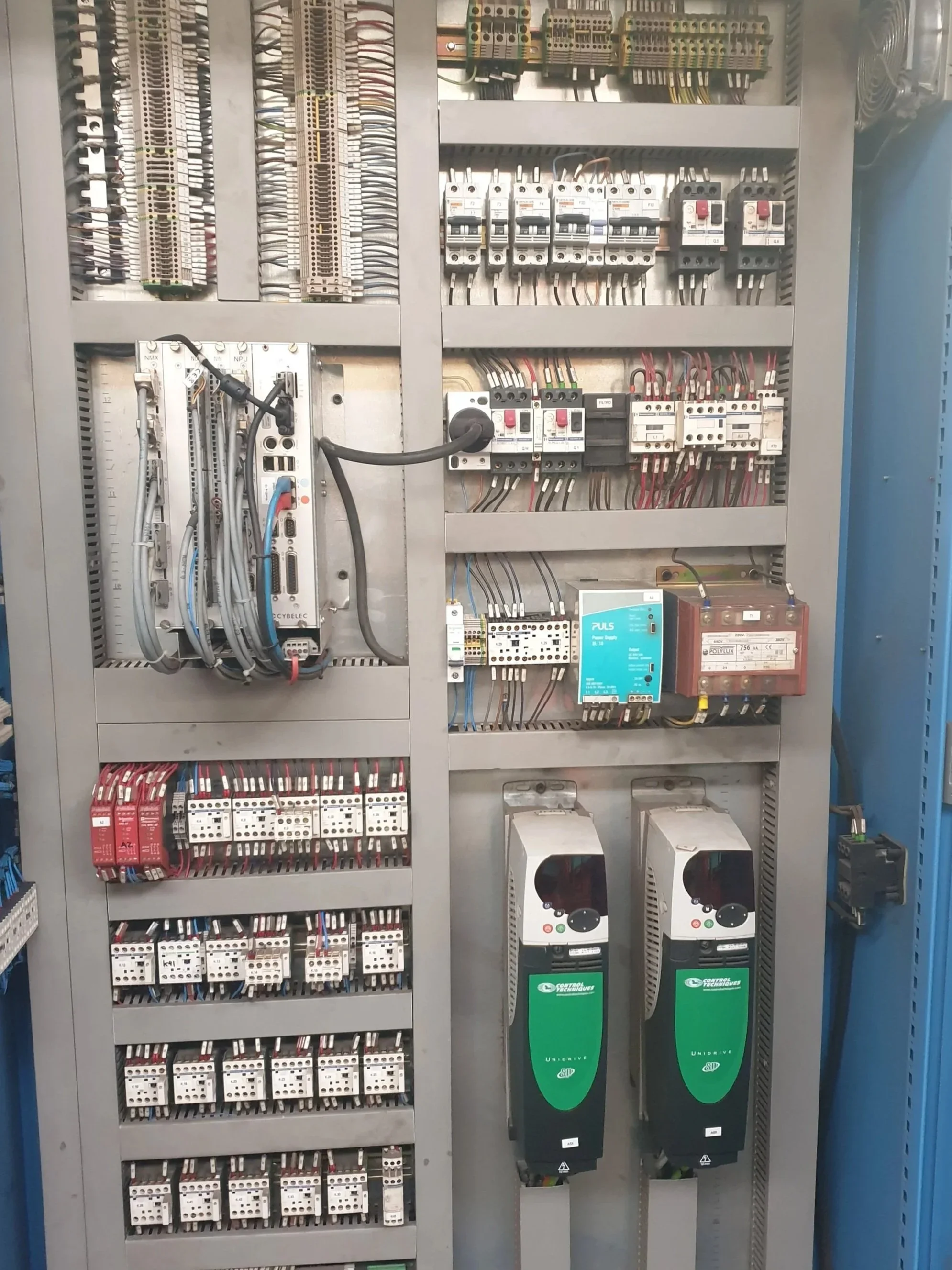 Panel eléctrico con componentes y circuitos eléctricos internos, incluyendo disyuntores, relés y variadores de frecuencia.