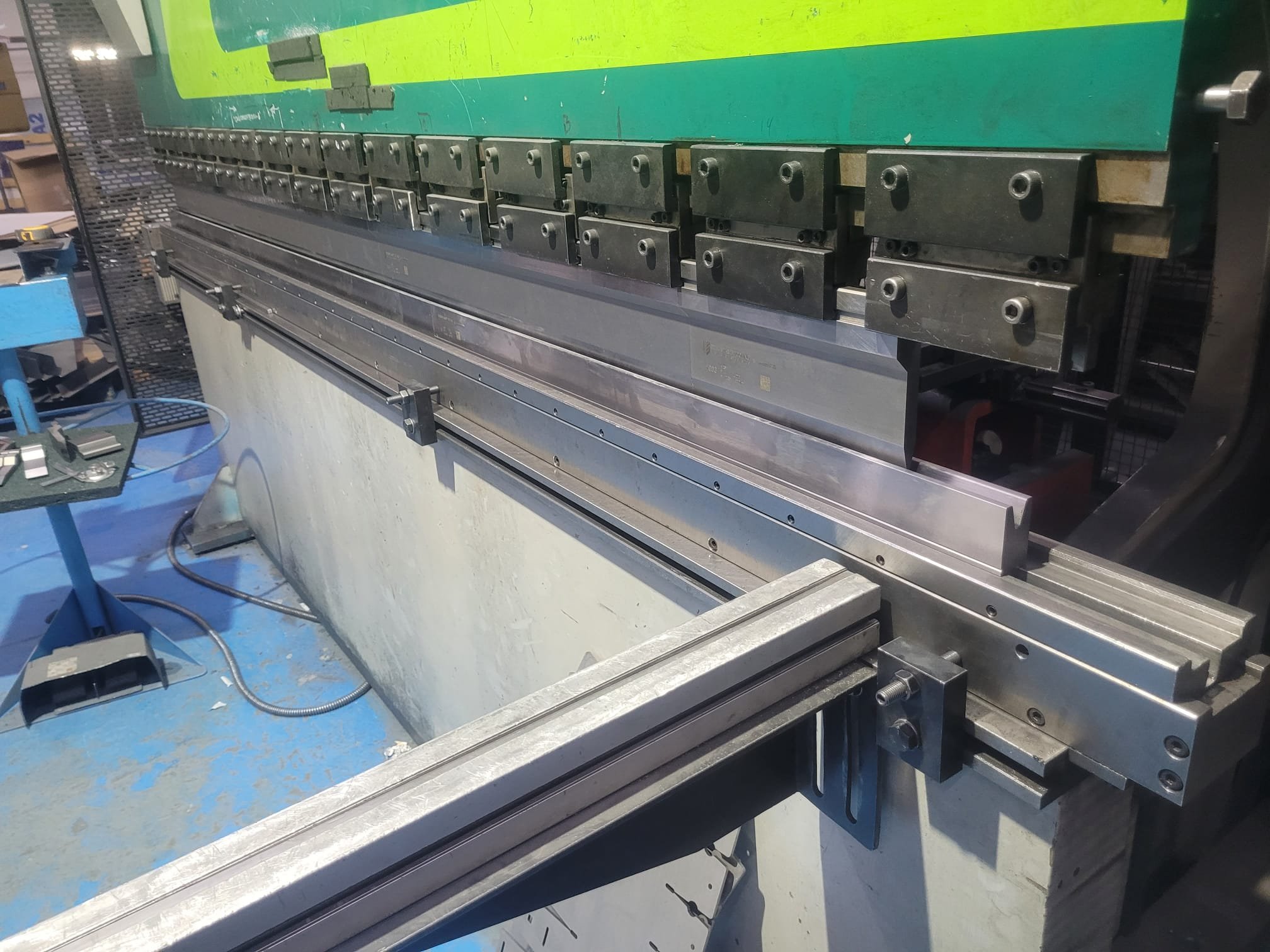 Prensa hidráulica industrial de corte con una superficie metálica y componentes mecánicos en un taller de fabricación.