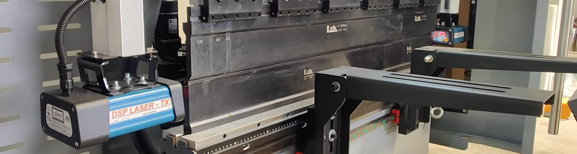 Máquina de corte con láser en un taller de fabricación, con componentes metálicos y controles visibles.