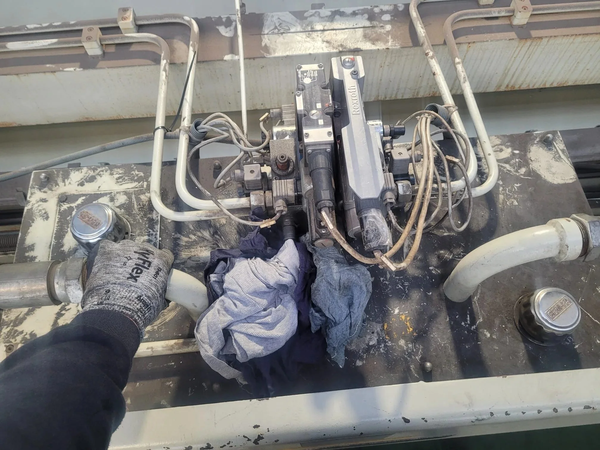 Válvula y tuberías industriales en una máquina de proceso, con herramientas y prendas de trabajo.