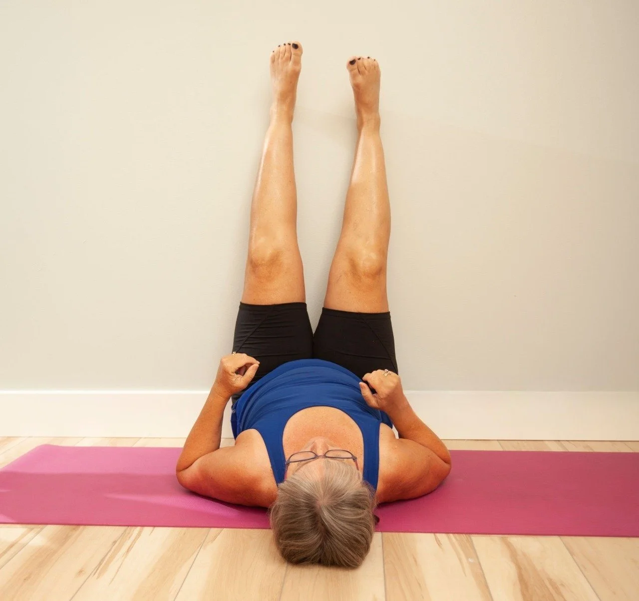 person lying on mat with legs elevated on wall