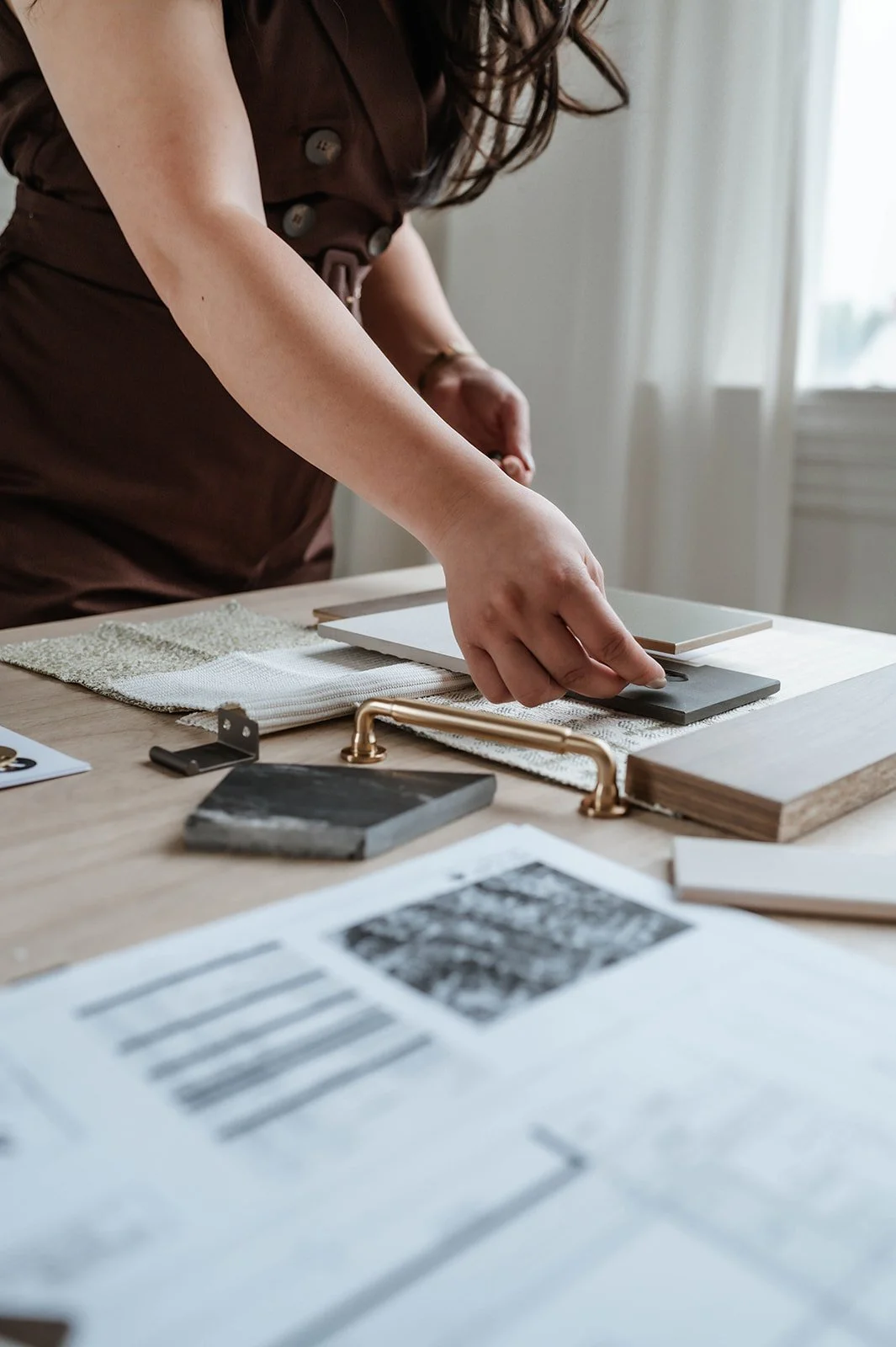 Person arranging sample tiles or materials on a table in a well-lit room.