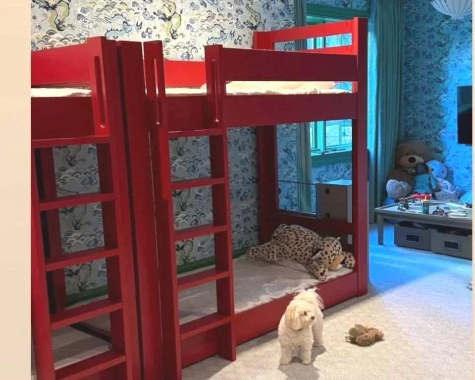 A bedroom with a red loft bed, a small white puppy, and plush toys including a cheetah and teddy bear.