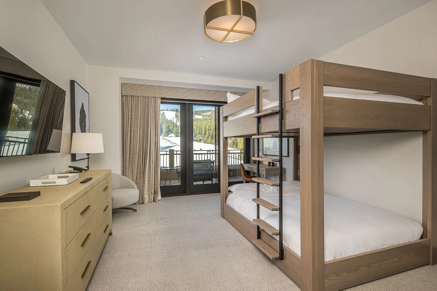 Hotel room with a bunk bed, a dresser, a chair, a TV, and a balcony with mountain views.