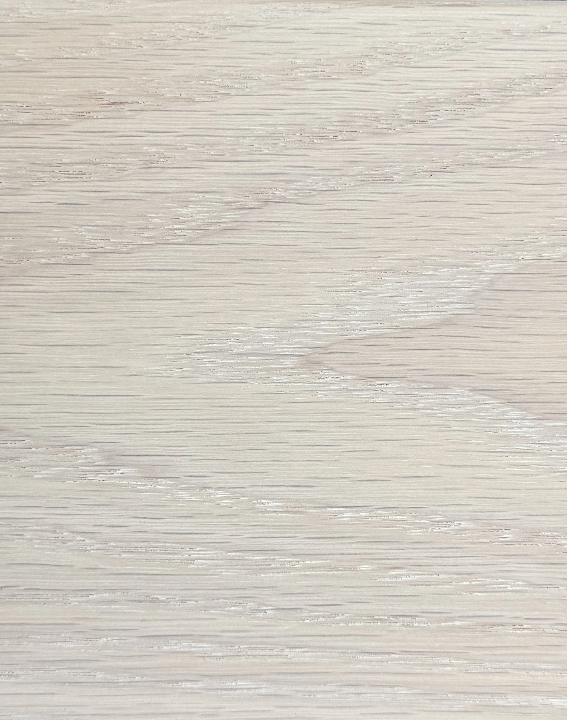 A hand holding a small, light-colored wooden block against a white wall with some texture.