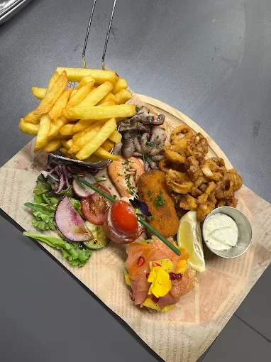Assiette de nourriture comprenant des frites, viande en sauce, salade avec tomates, radis et salade verte, une tranche de citron, du tartare, et du poulet frit avec une portion de sauce - Aftersport Clavier