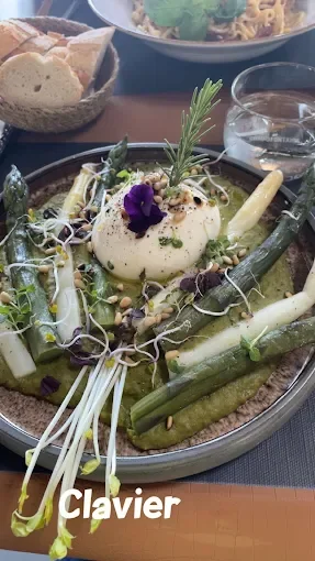Assiette de légumes avec un œuf, garnie d'une branche de romarin, d'une violette et de germes, avec du pain à côté - Aftersport Clavier