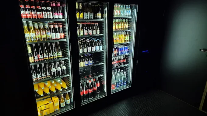 Vitrine réfrigérée avec diverses boissons gazeuses colorées et bouteilles isolées, dans un espace sombre - Aftersport Clavier