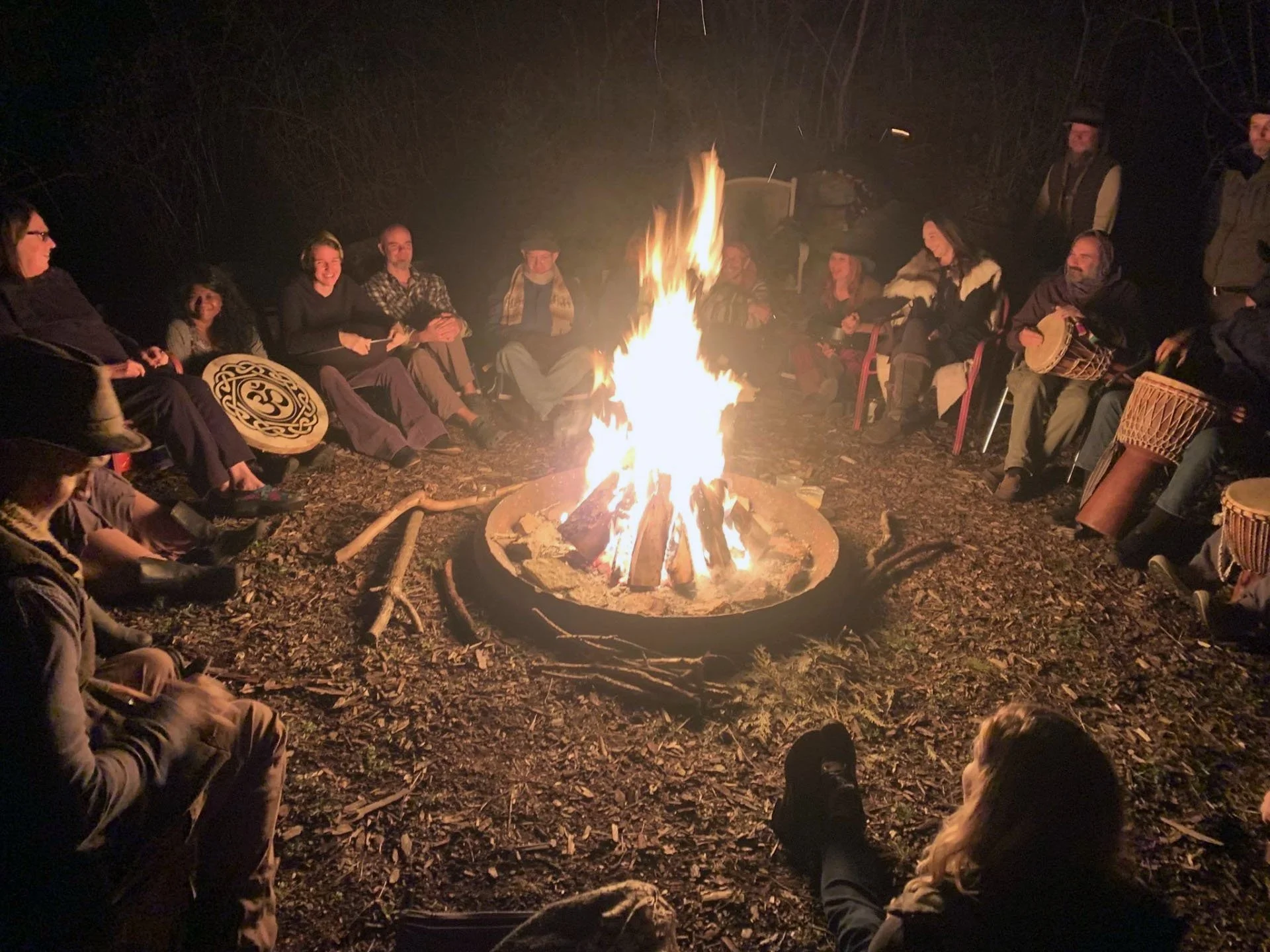 People sitting in a circle around a campfire at night.