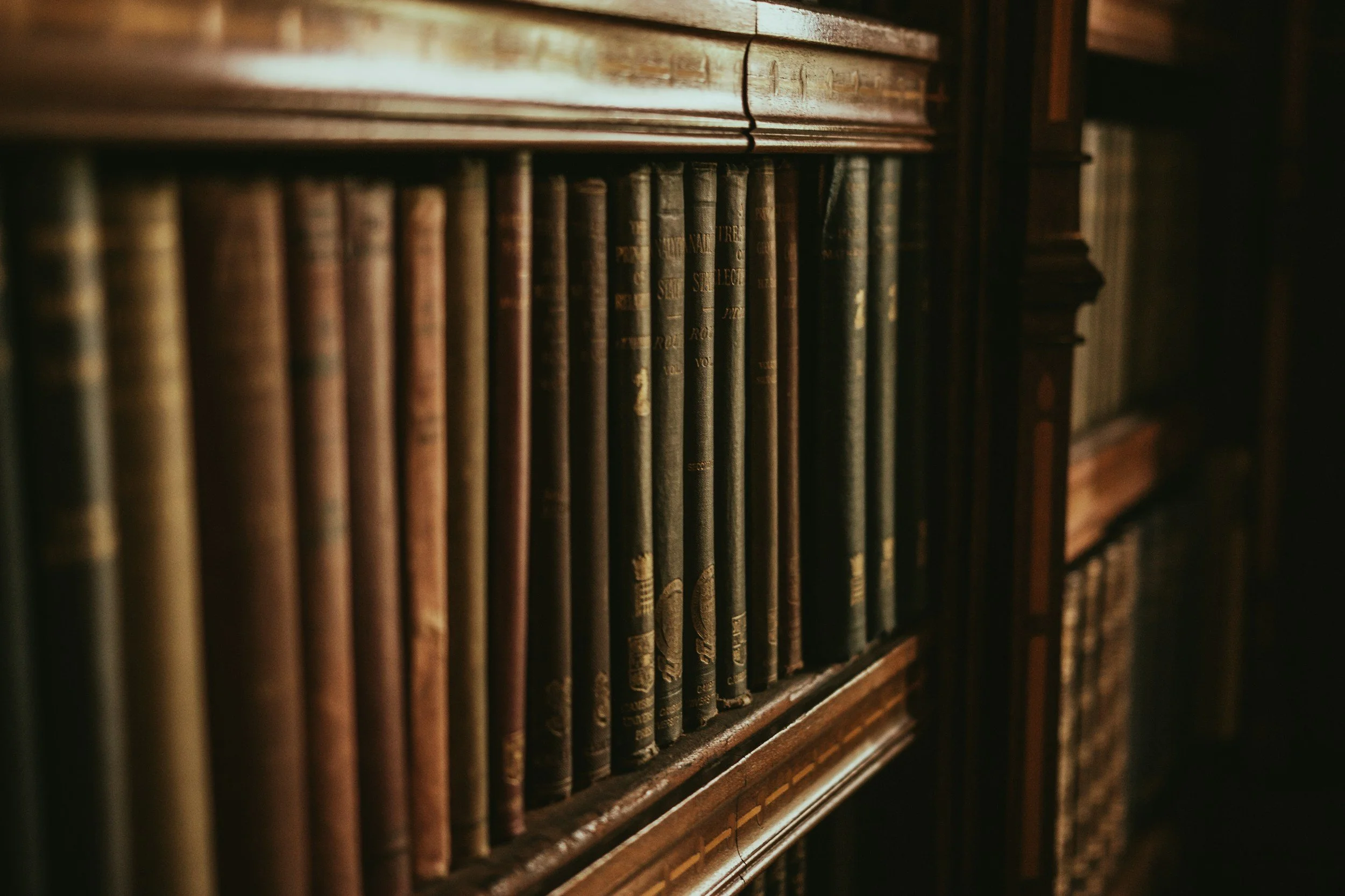 A bookshelf filled with old, worn books in a dimly lit room.