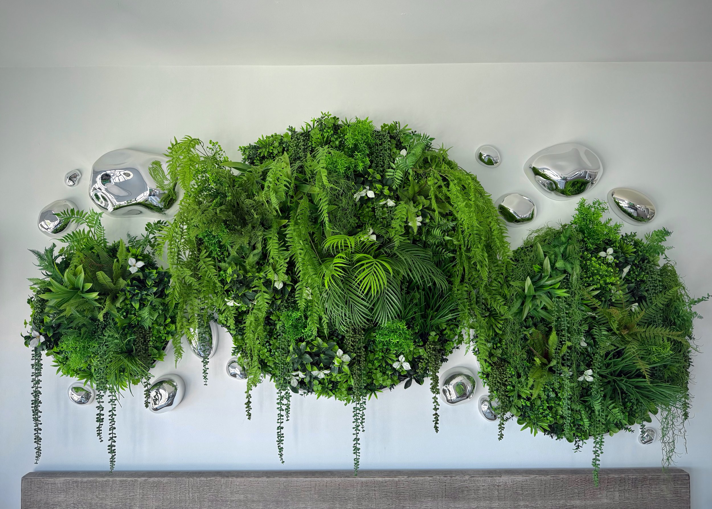 A luxury custom-made faux lush botanical plant triptych art piece positioned about a Restoration Hardware designer bed frame.