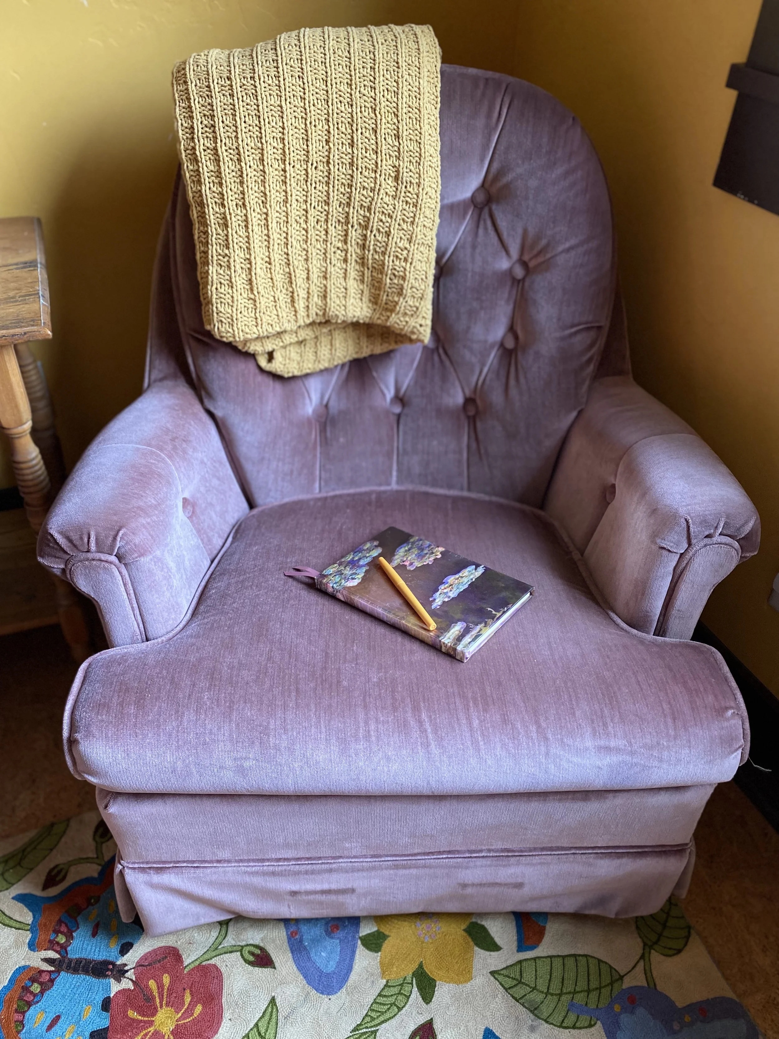 A lavender velvet armchair draped with a gold blanket in a room with yellow walls. A journal with a yellow pencil sits on the cushion.
Coaching, emotions, neuroscience, brain science, life coach, processing, support, feelings, help,