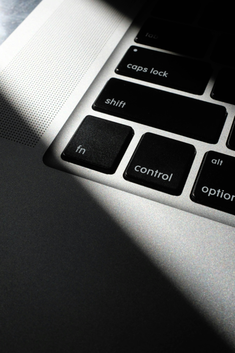 Close-up of a laptop keyboard focusing on the 'fn', 'control', 'alt', and 'option' keys, with part of the trackpad and laptop body visible.