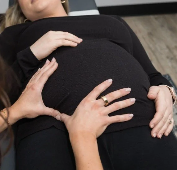 Hands resting on a pregnant belly representing prenatal chiropractic care in West Ashley, Charleston SC