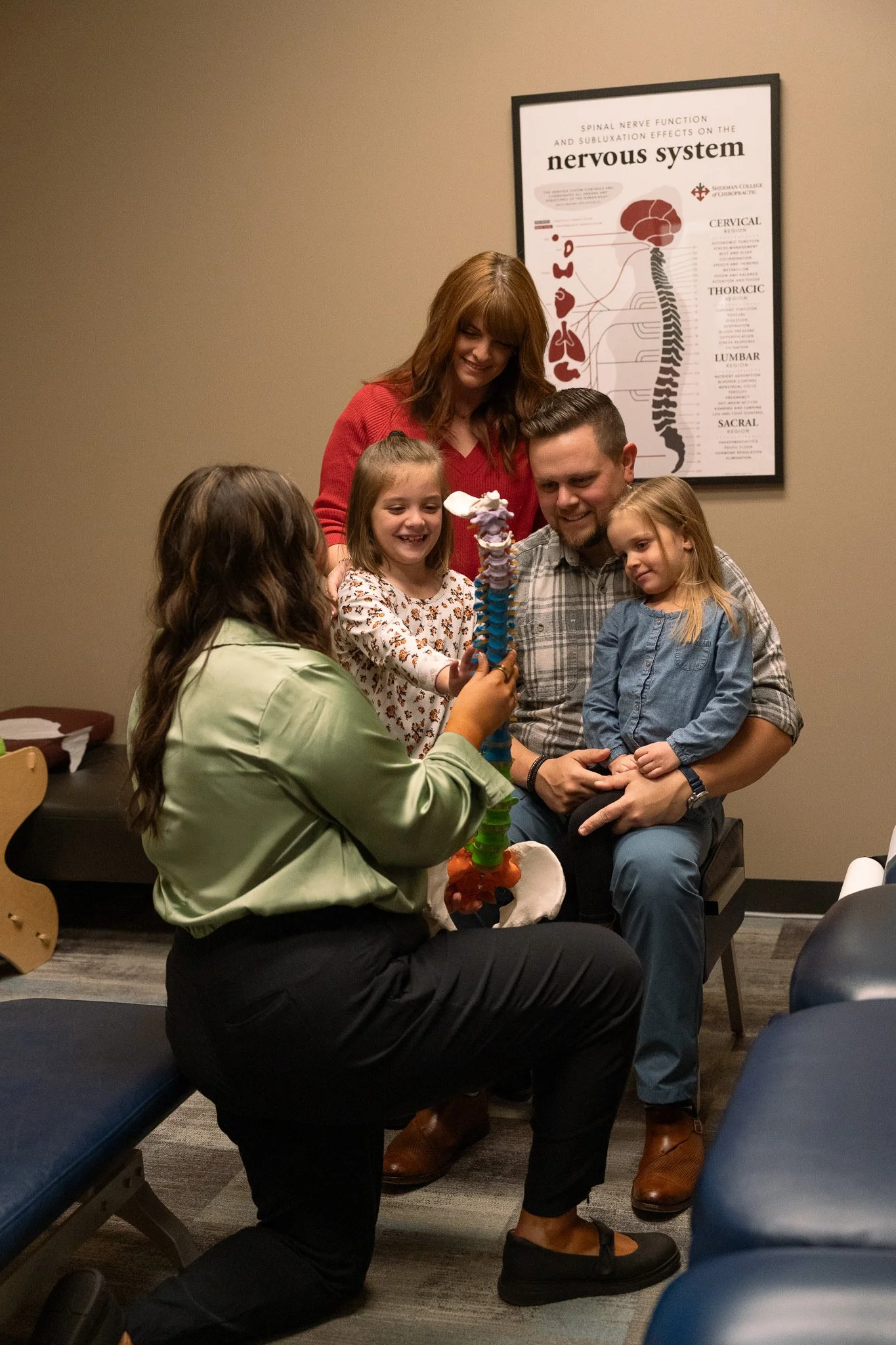 Dr. Sophia Duarte showing a spine model to a family during a chiropractic consultation at Radiant Chiropractic in West Ashley, Charleston, SC.