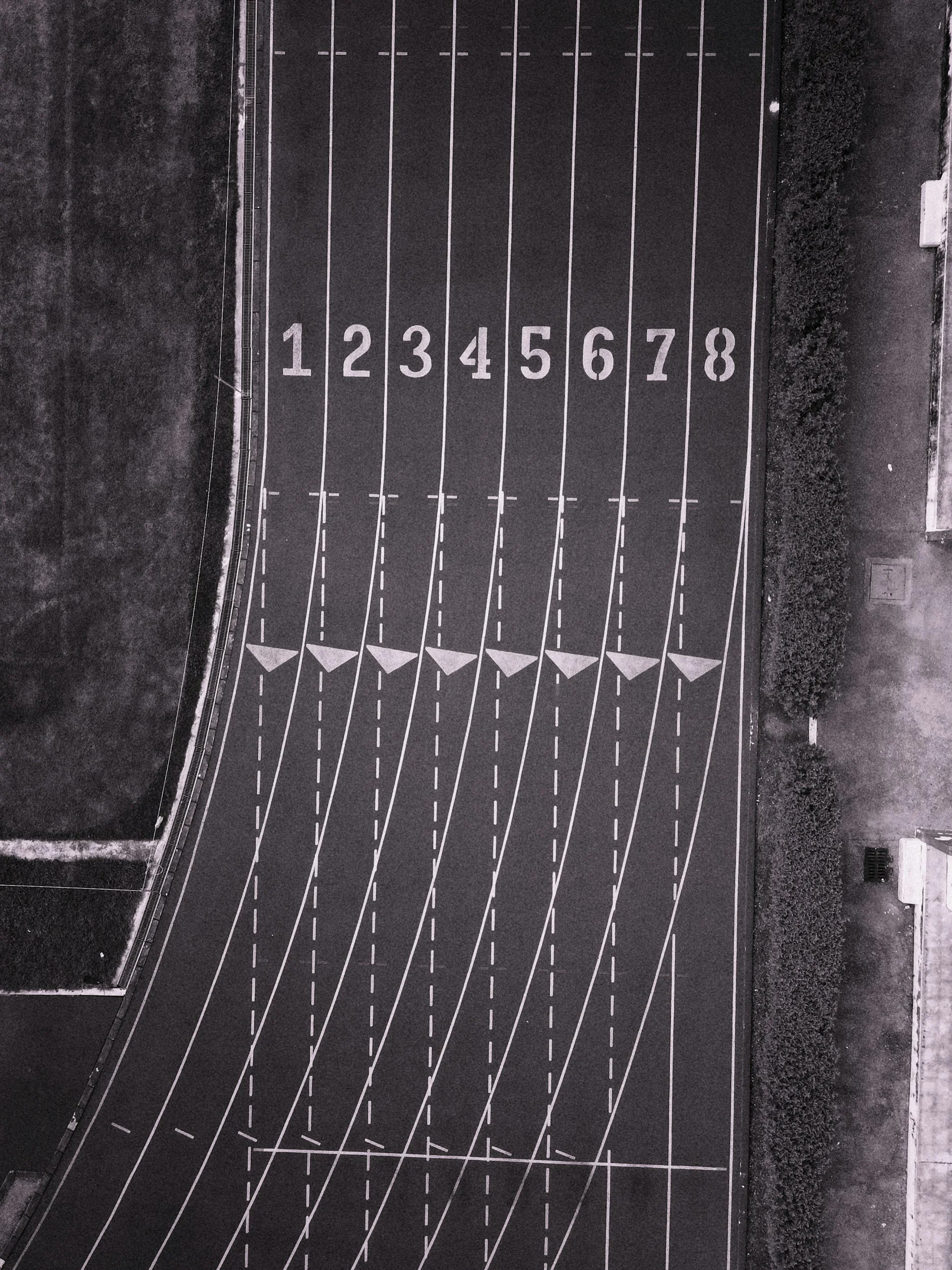 An urban scene with a running track or road marked with white lines and numbers from 1 to 8, viewed from above.