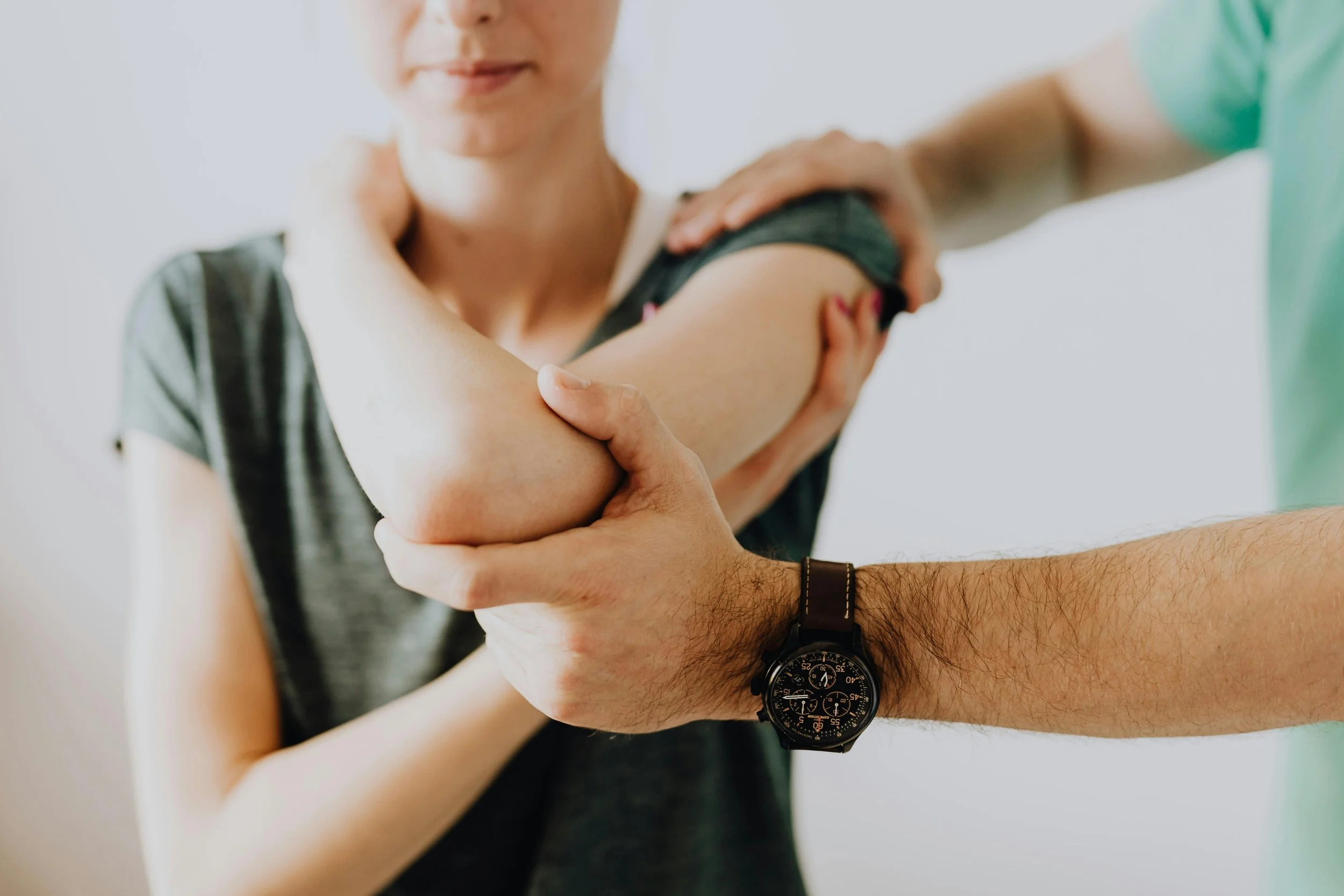 A woman receiving a shoulder massage from a man wearing a watch.