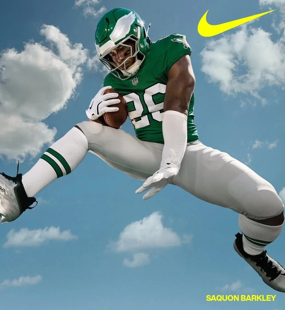 Football player Saquon Barkley flying through the air holding a football.