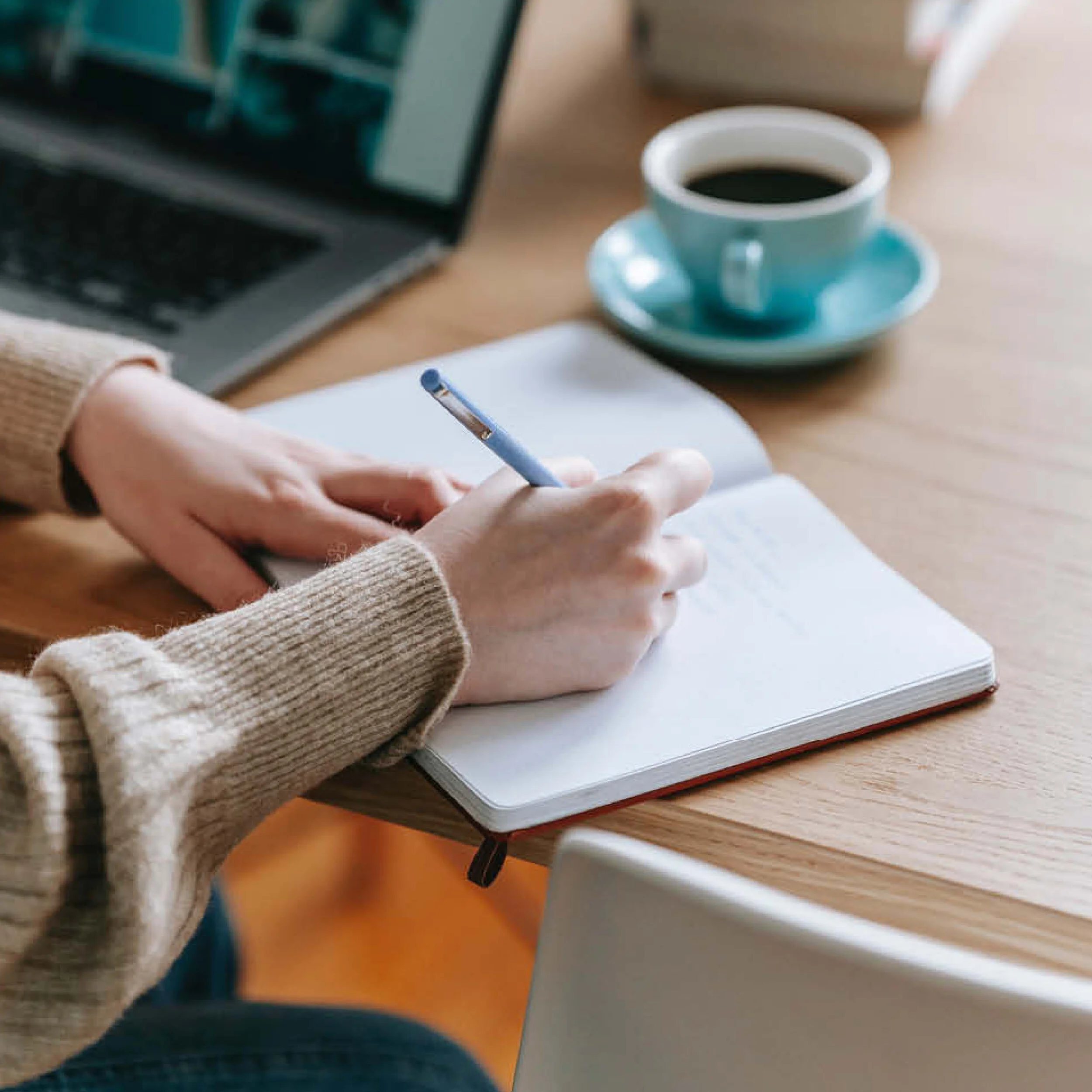 Image of woman writing the story of Rose Street Digital in a book with a blue pen.