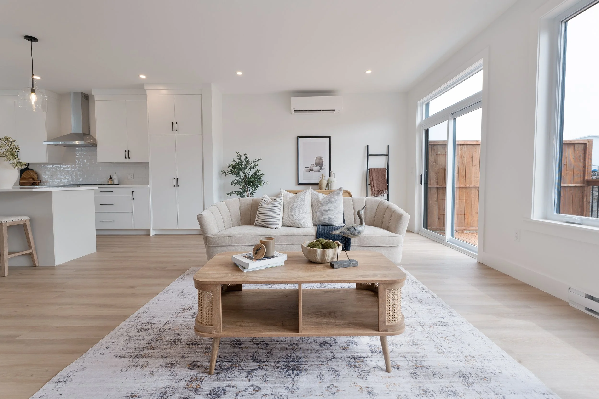 Nova Scotia, Halifax real estate photography and marketing for MLS. Bright modern living room with beige sofa, wooden coffee table, and large windows in a white and neutral decor style.