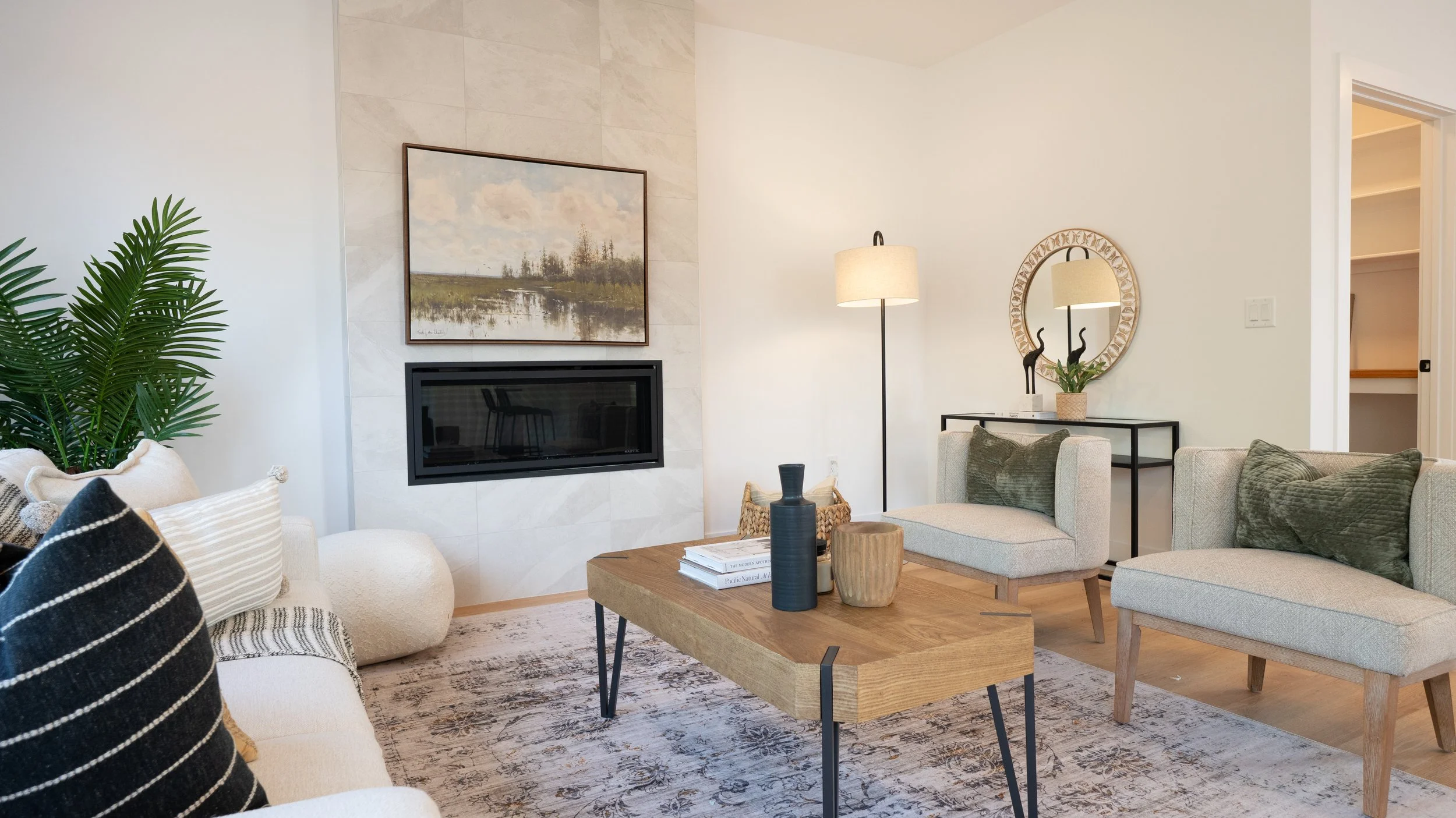 Professional high quality Halifax Nova Scotia real estate photography. MLS Listing Photo. Living room with beige sofa and armchair, wooden coffee table, fireplace, large plant, and decorative items including vases and a mirror.