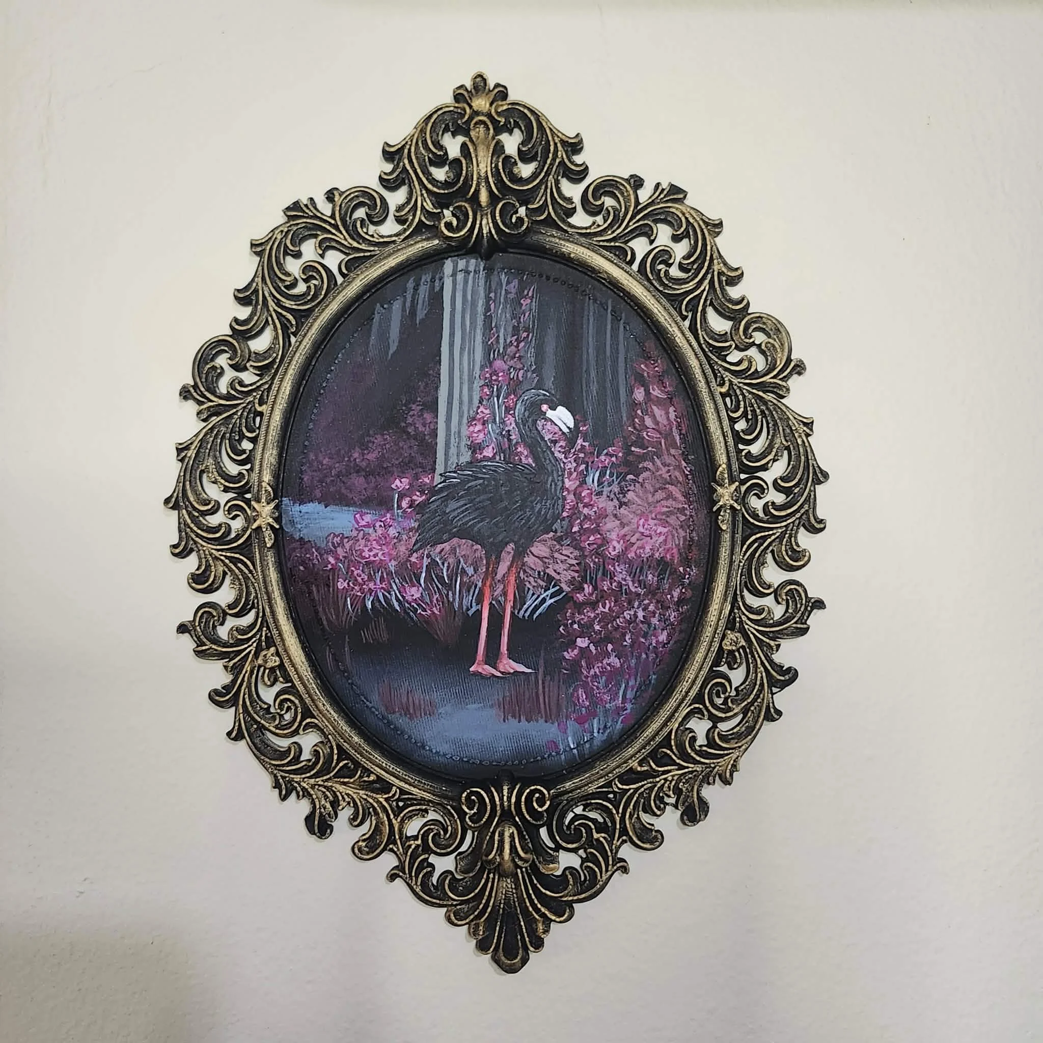 Painting of a black flamingo standing in a lush, pink, jungle-like setting with waterfalls in the background, framed by an ornate, gold, Victorian-style frame.