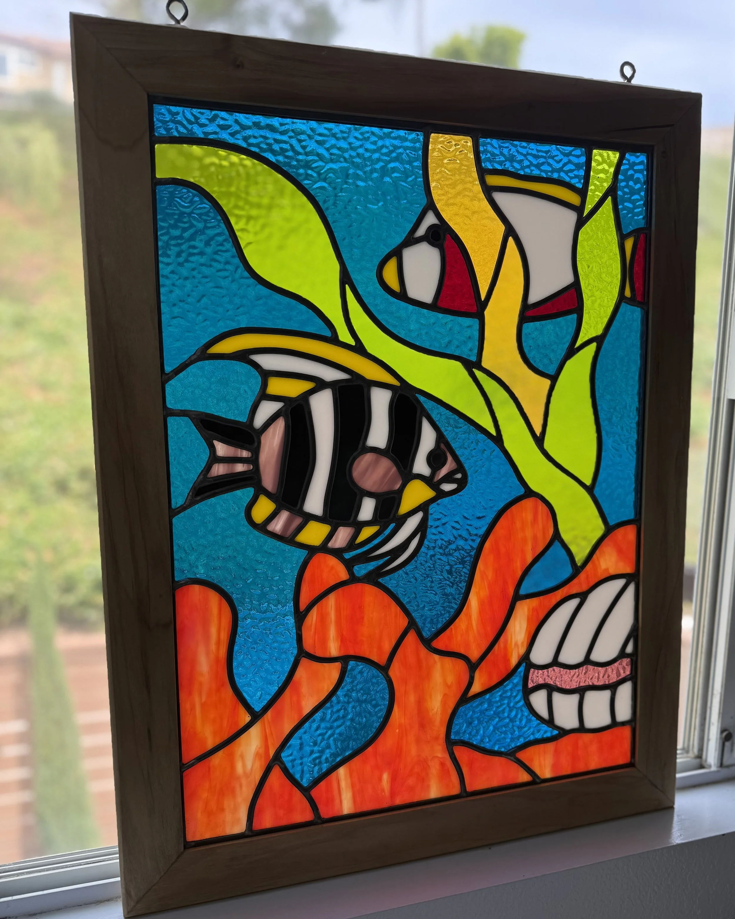 Colorful stained glass window depicting a tropical fish and a sea anemone.