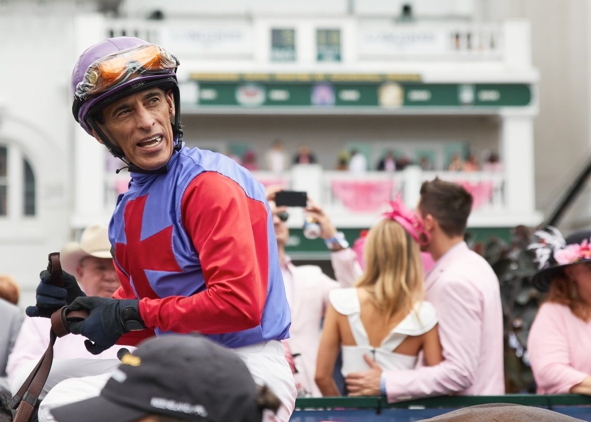 Jockey in racing silks wearing helmet at the horse race with spectators in the background.