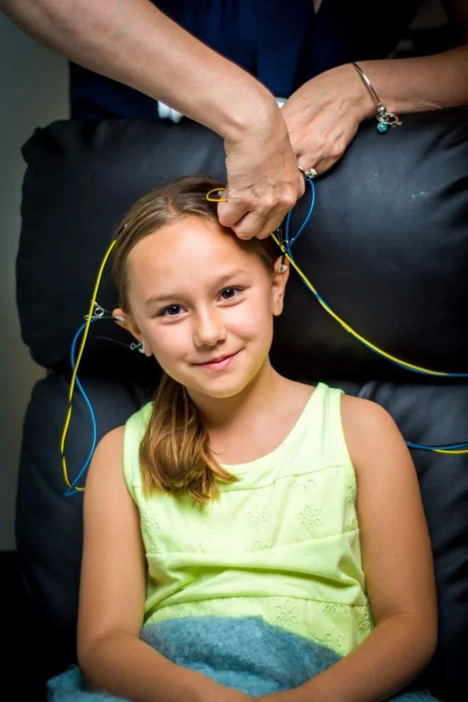 A child participating in a neurofeedback session while EEG sensors are adjusted