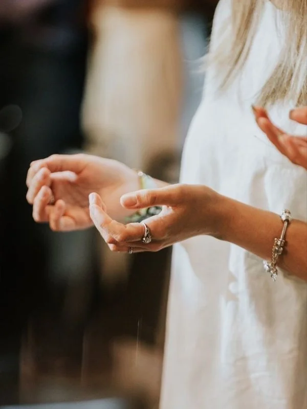Close-up of a woman's hands, worshipping God with other christians.
