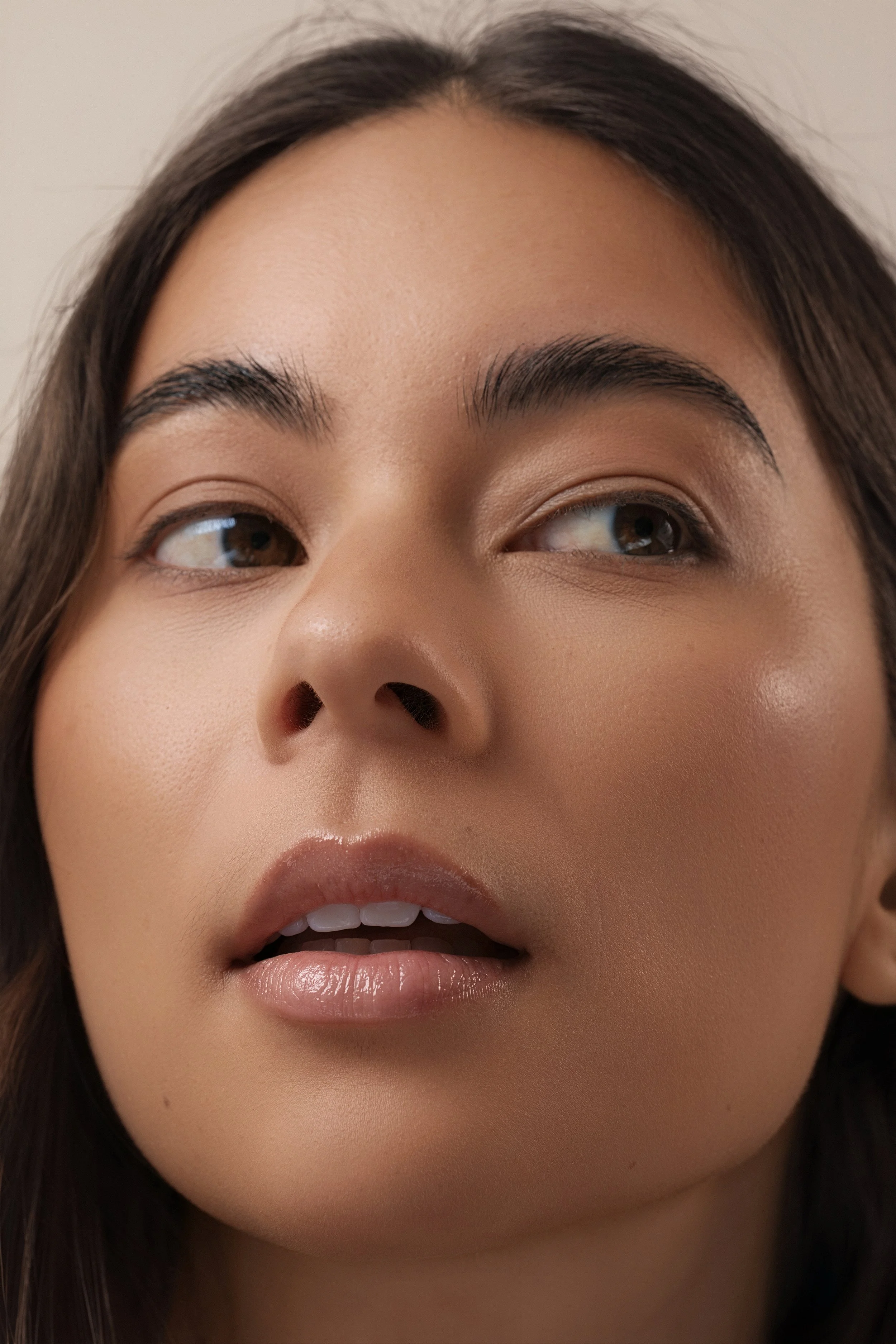 Close-up portrait of a young woman's face showing part of her lips, nose, and eyes. She has dark hair and well-groomed eyebrows.