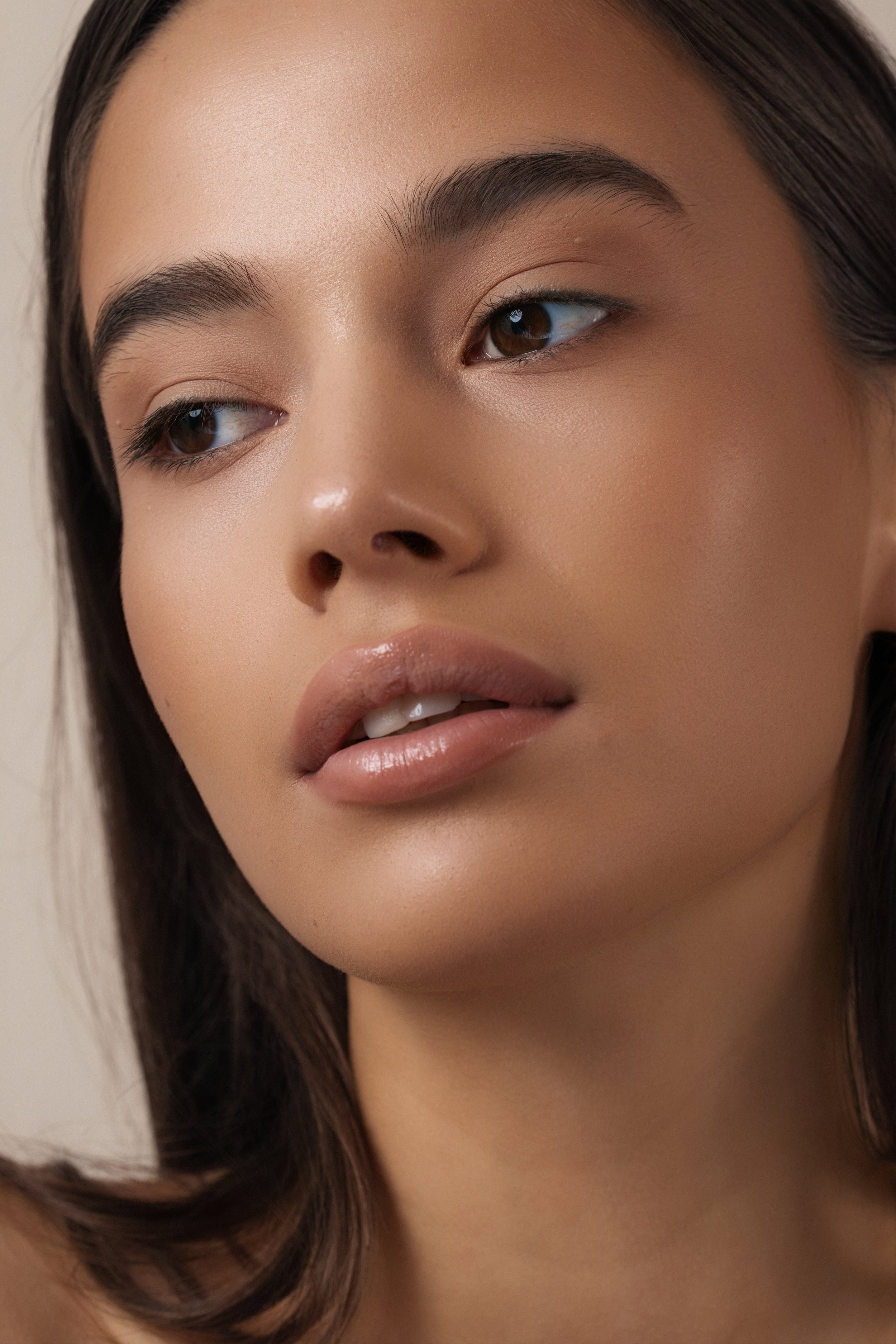 Close-up of a woman's face focusing on her eye, eyebrow, and lips with smooth skin and dark brown hair.