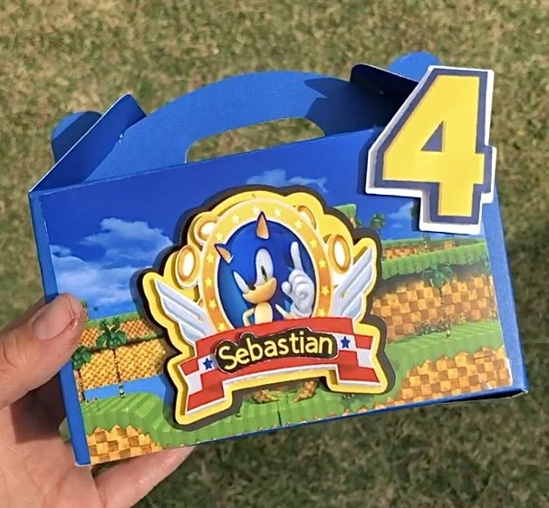 Custom Sonic the Hedgehog-themed lunchbox with the number 4 and a Sonic logo, held outdoors over grass.