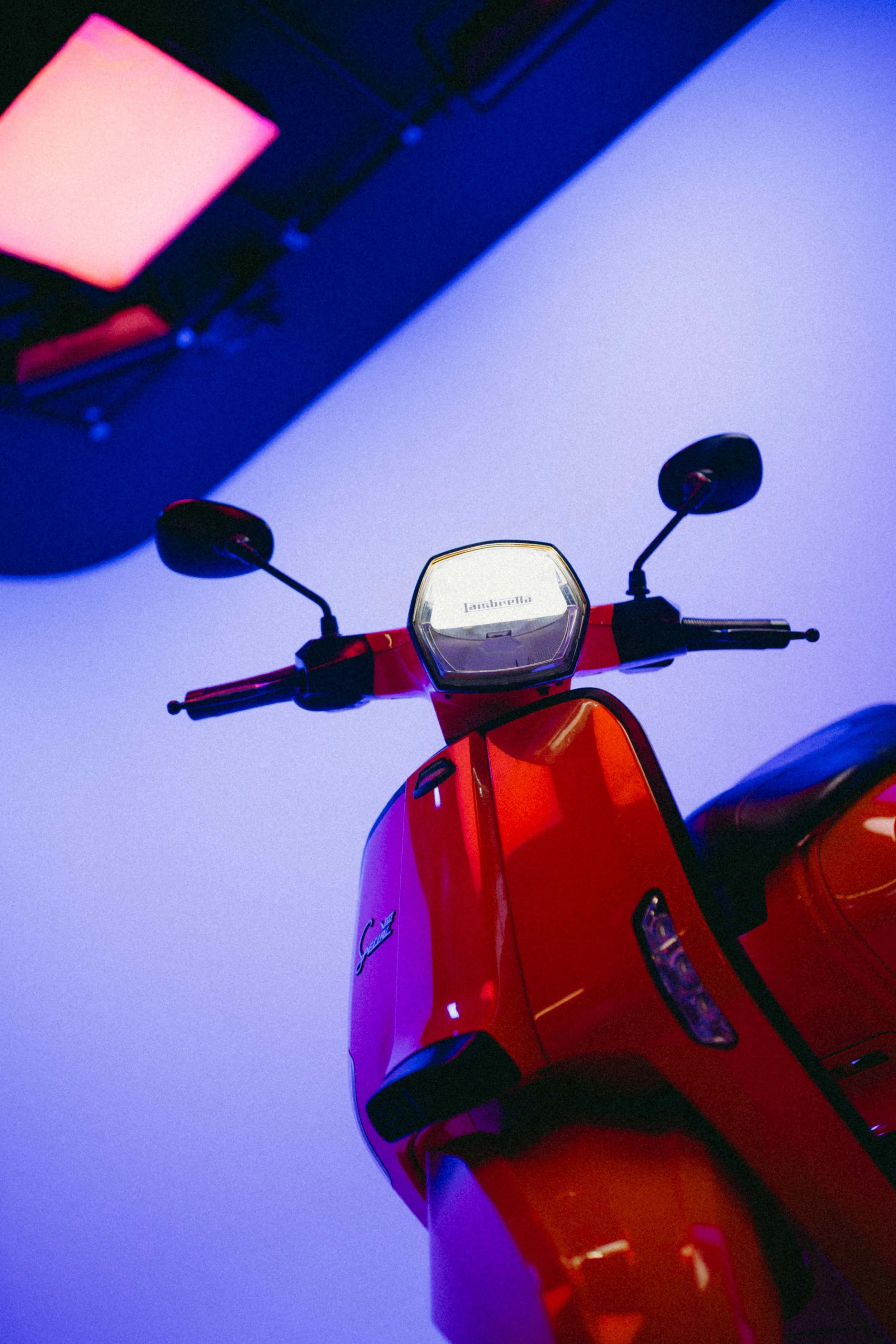 An orange scooter on a cyclorama with a purple and blue background.