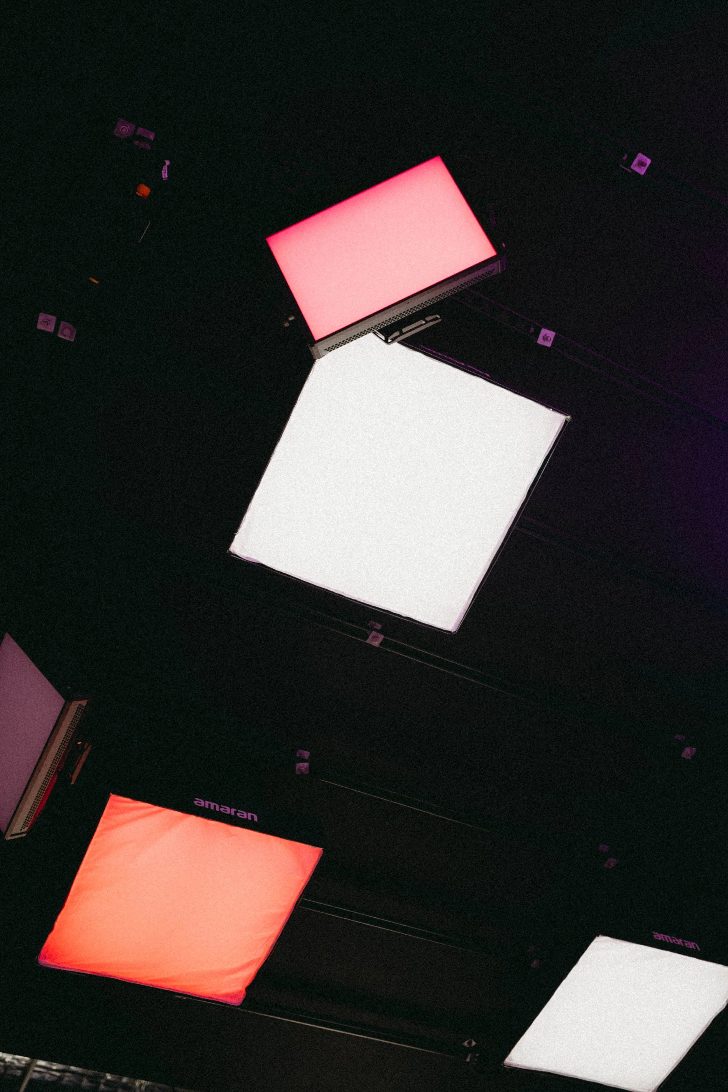 Ceiling with multiple square LED light panels in white, red, and purple colors.