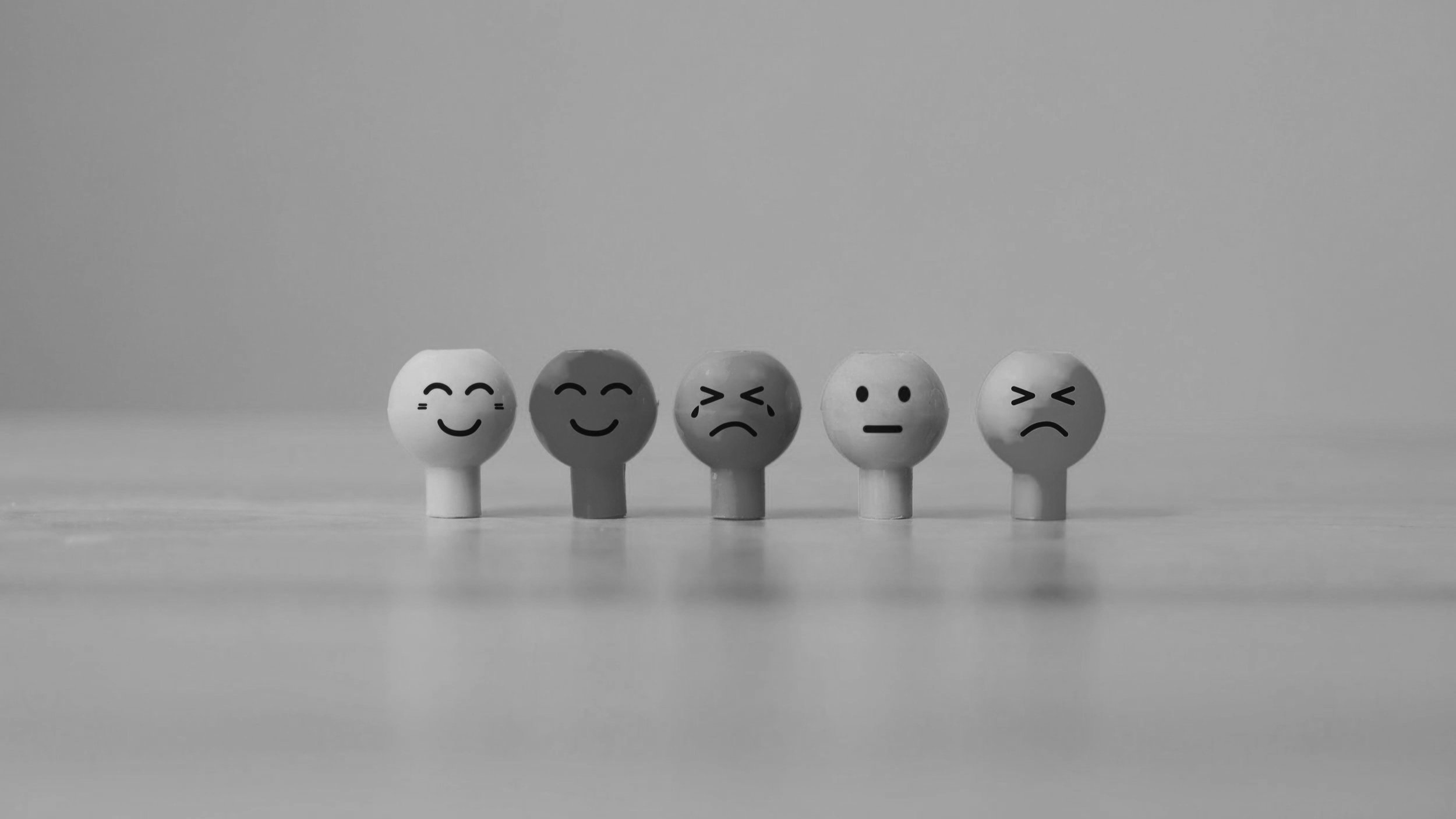 A line of facial expressions drawn in cartoon line style on wooden things.