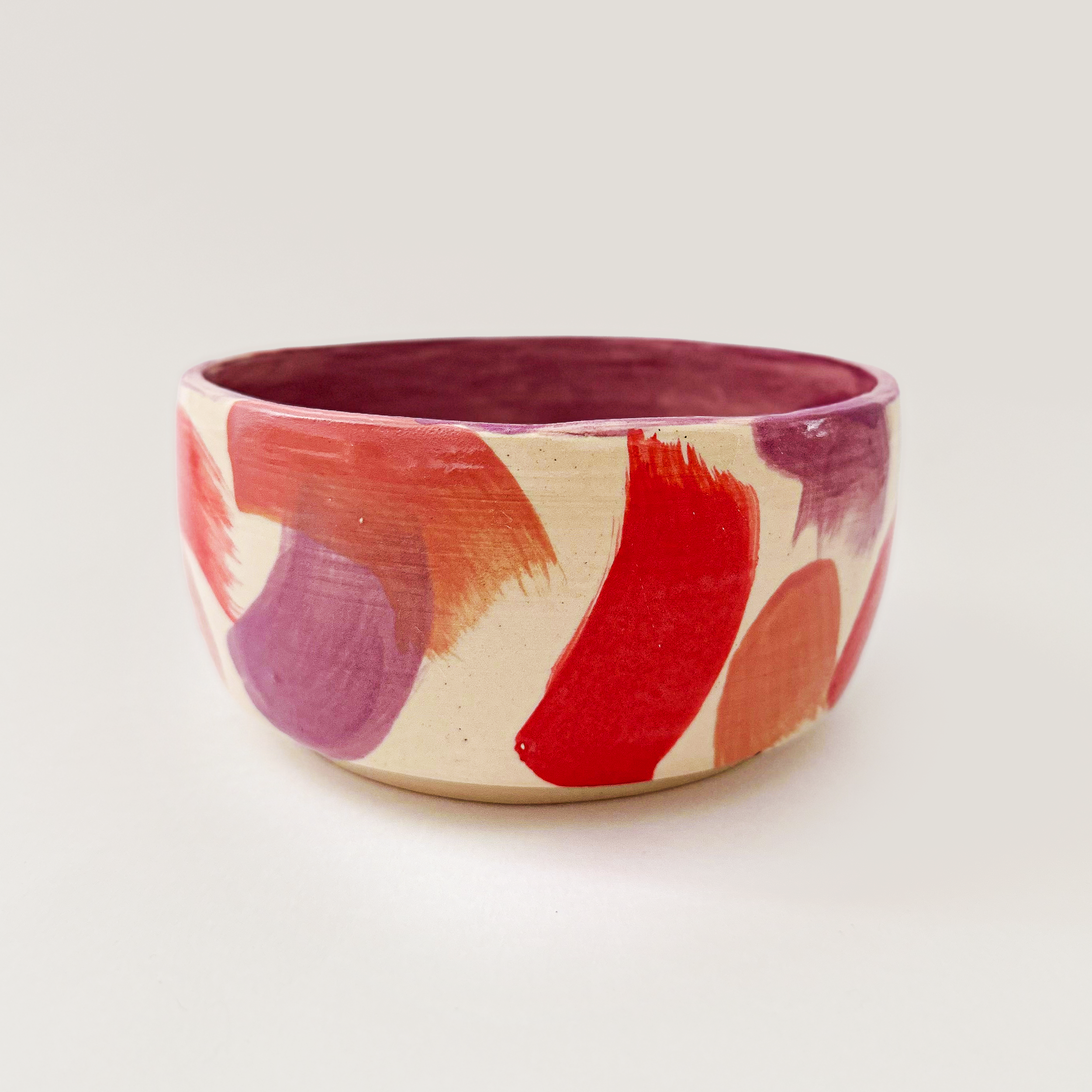 ceramic planter with colorful brushstrokes in red purple and coral.