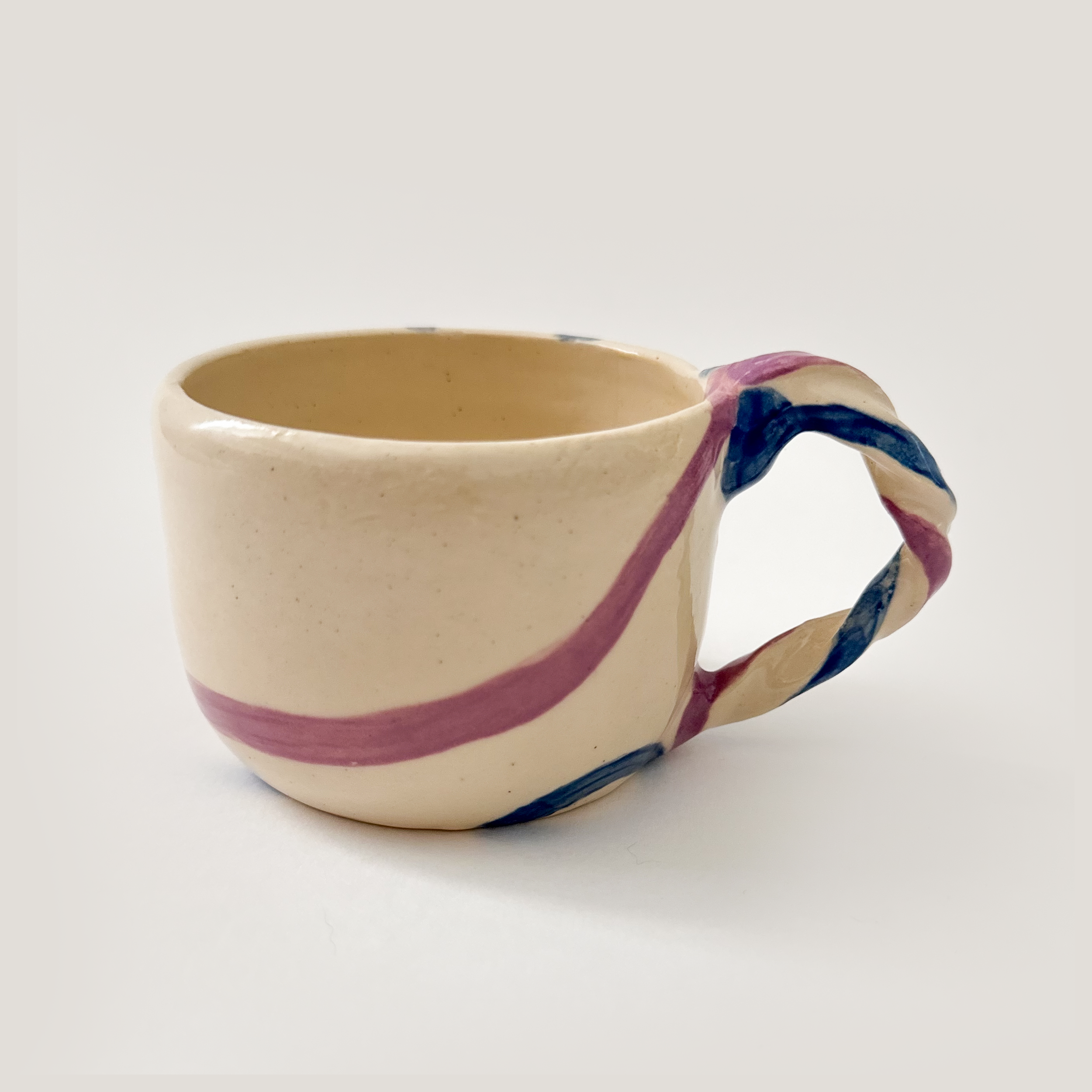 cream ceramic mug with twisted handle and painted purple and navy accents
