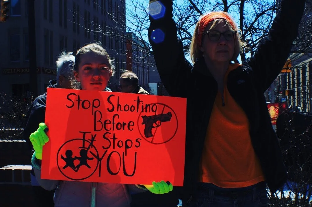 March, 2018. Taken at an Enough is Enough Protest in Easton, Pennsylvania. A young girl with a sign that says "Stop Shooting before it stops you" a woman is next to her.