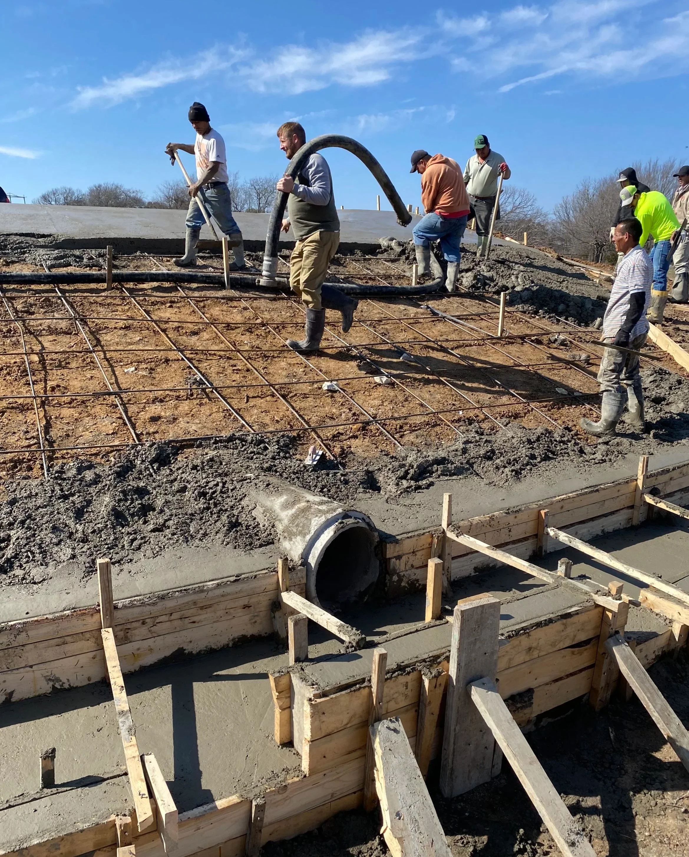 Raythorn Construction crew pouring structural concrete with rebar reinforcement and wood formwork on a commercial jobsite in Fort Worth, Texas — expert concrete contractors specializing in engineered slabs and precision flatwork across DFW.