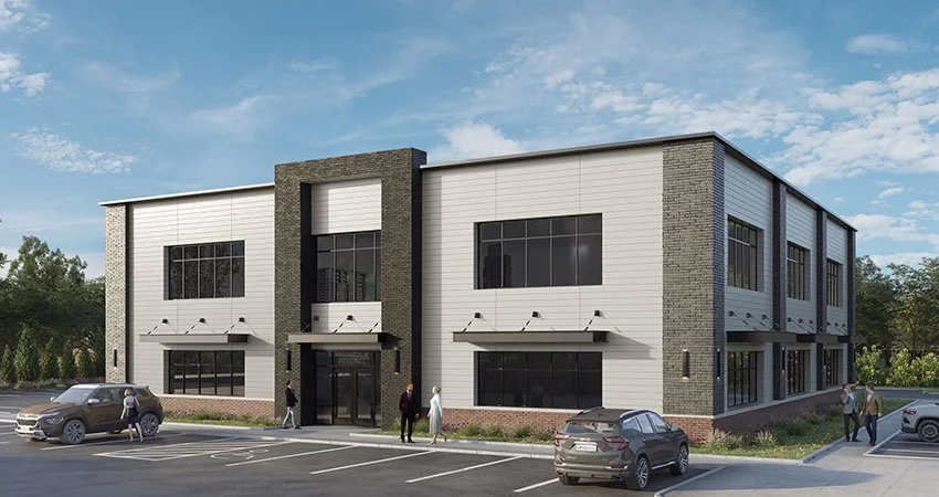 An industrial-style two-story commercial building with large black-framed windows and a black entrance door. It has a modern design with white siding, grey brick accents, and a flat roof. There is a parking lot with several cars and a few people walking outside.