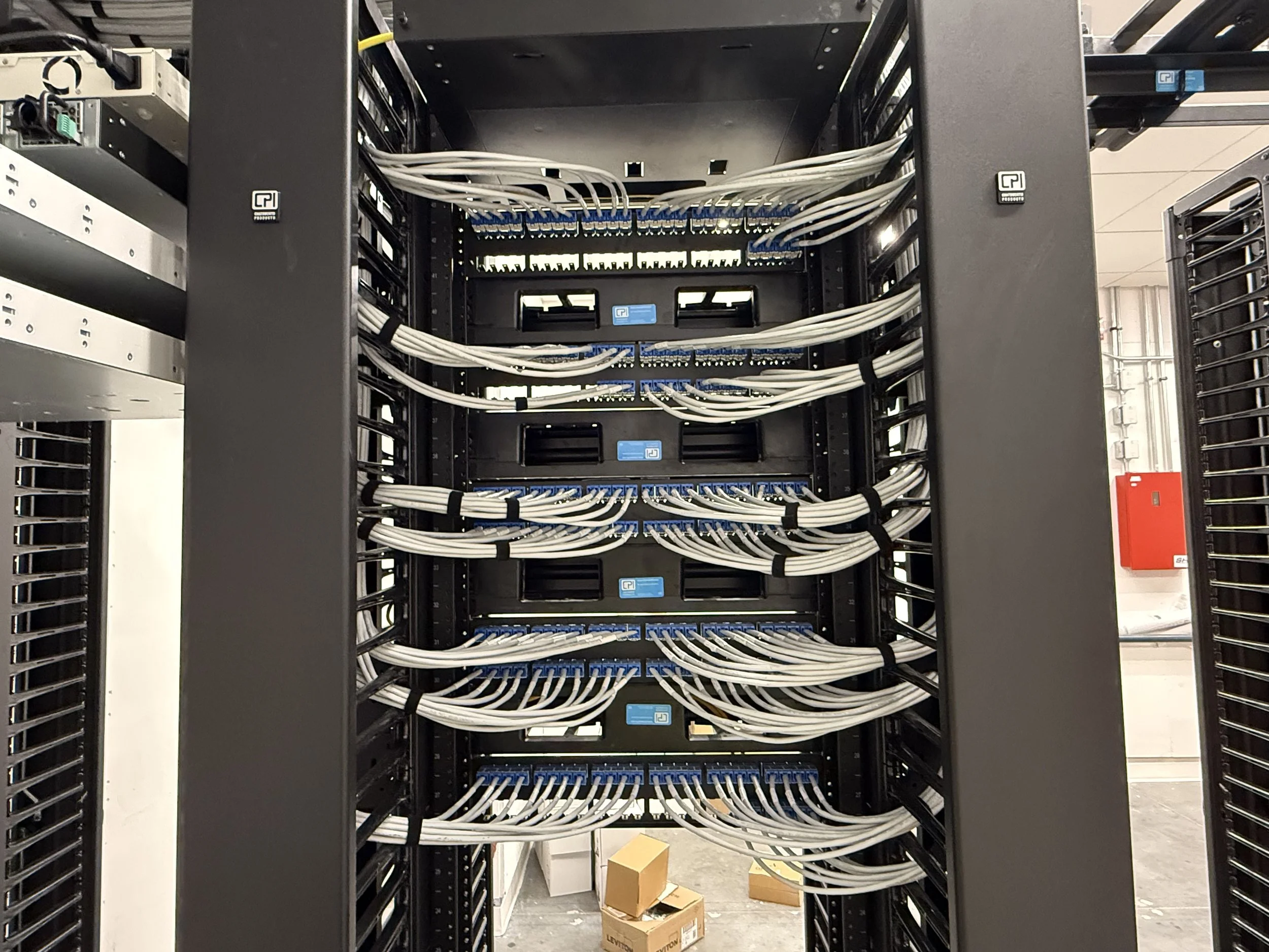 A server rack with organized network cables connected to blue network switches inside a data center.