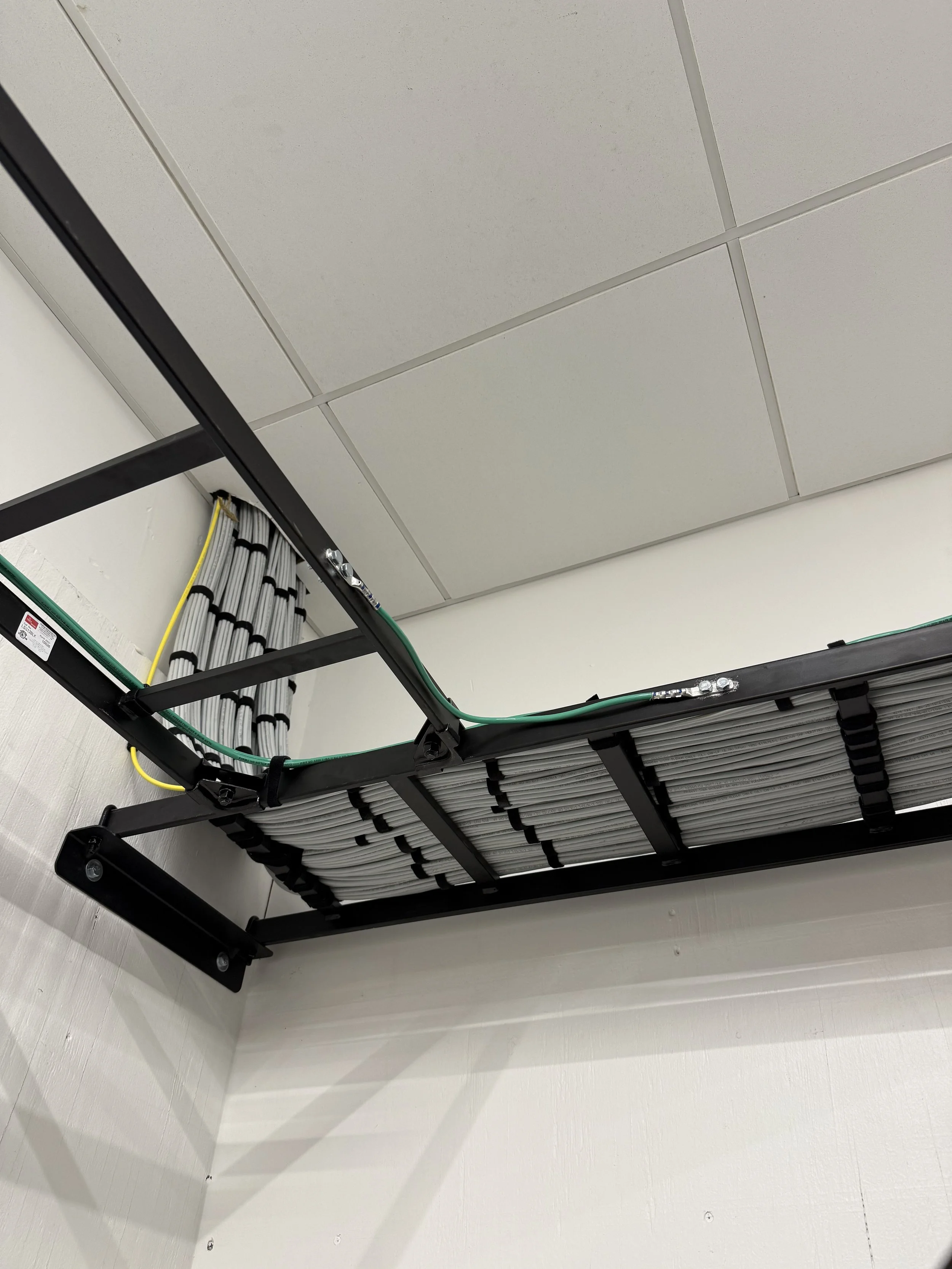 Ceiling grid with mounted equipment and cables, view from below.