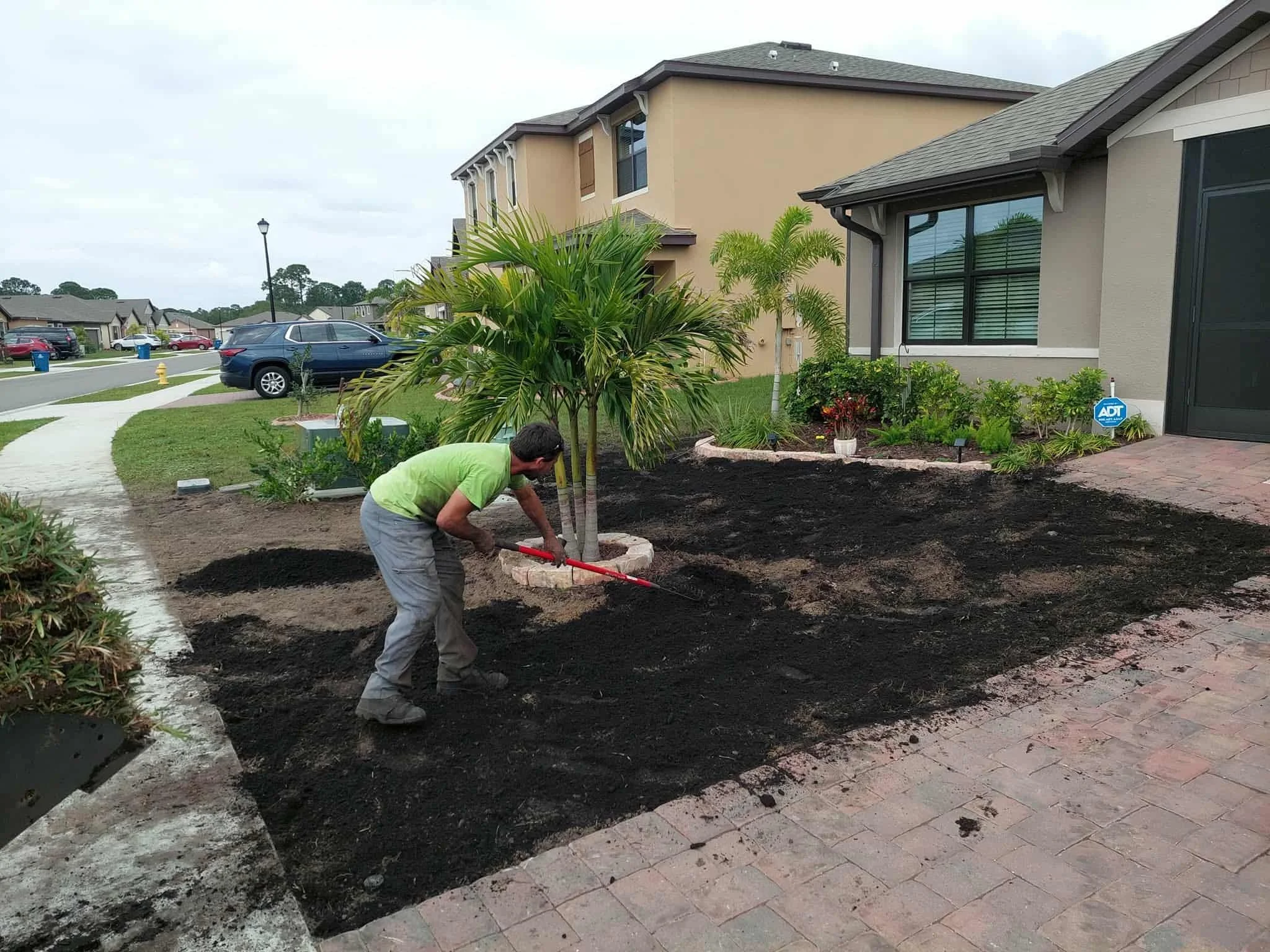 Person working on landscaping in front yard of house, planting or preparing soil for new plants.