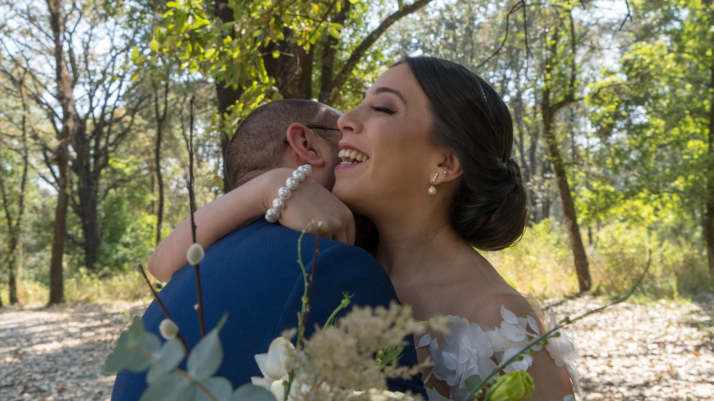 Pareja abrazada en un entorno boscoso, expresando felicidad y amor.