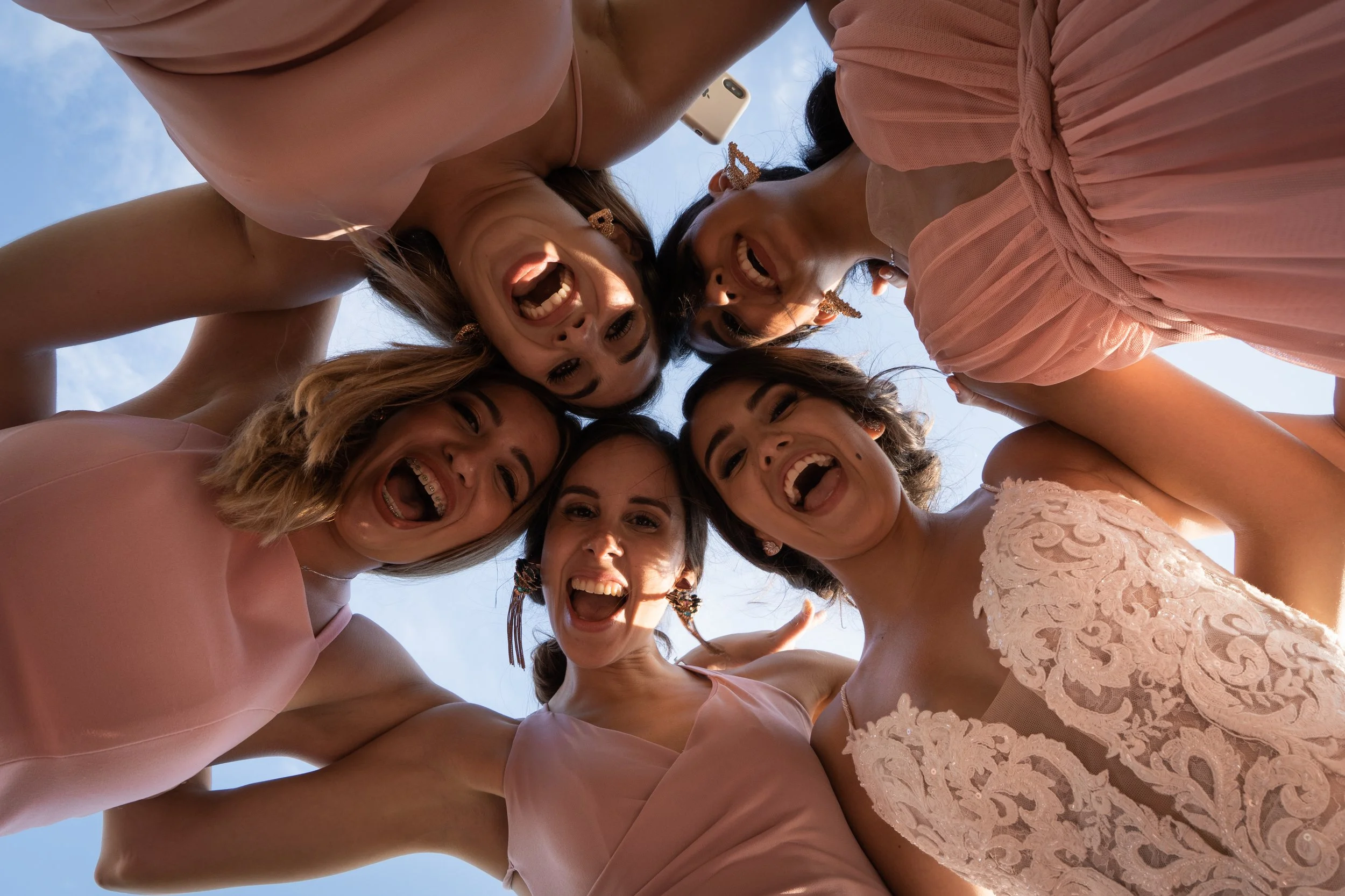 Grupo de chicas sonriendo y divirtiéndose, vistas desde abajo contra el cielo
