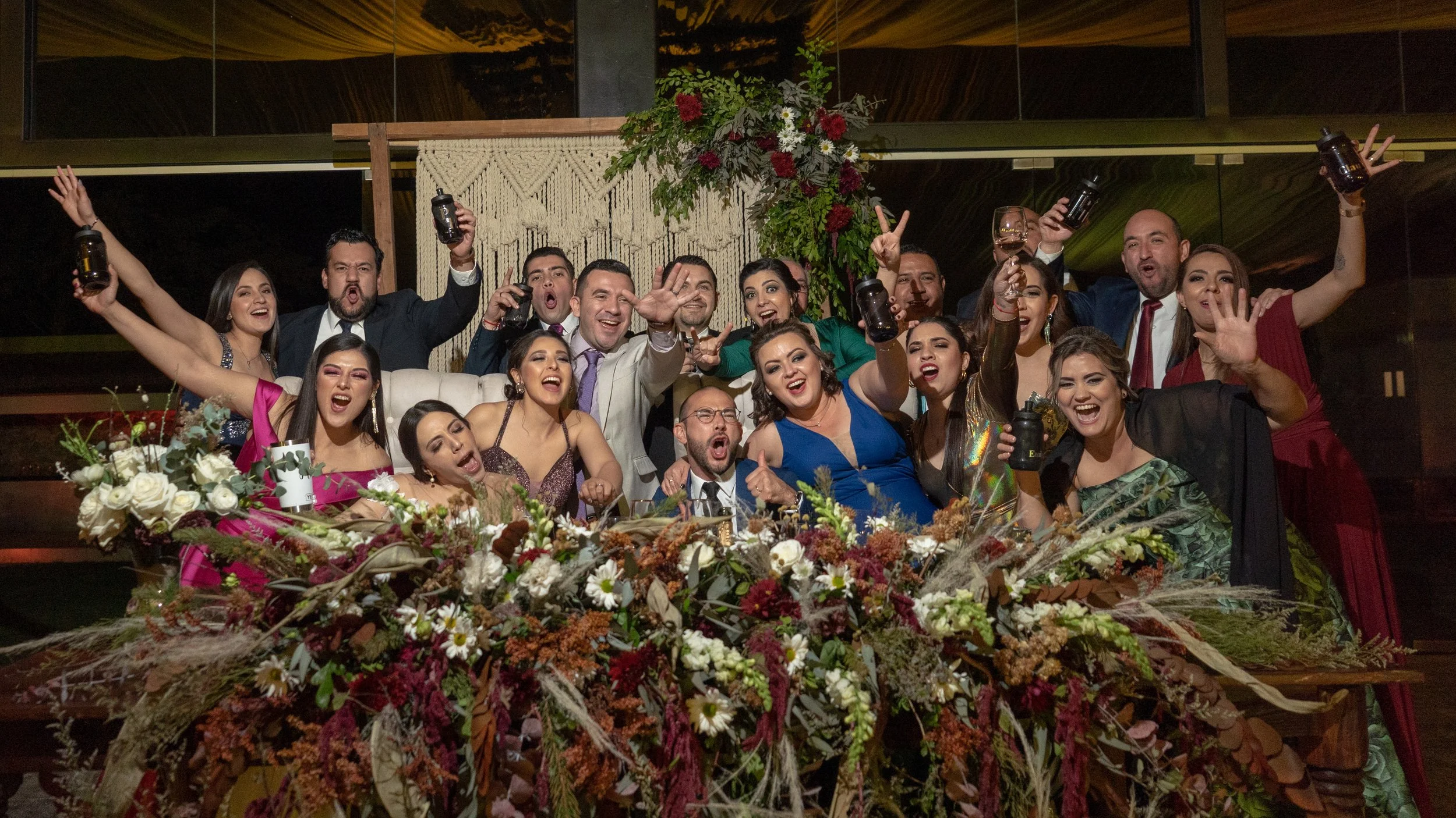 Grupo de personas celebrando en una fiesta con decoraciones florales y brindis.