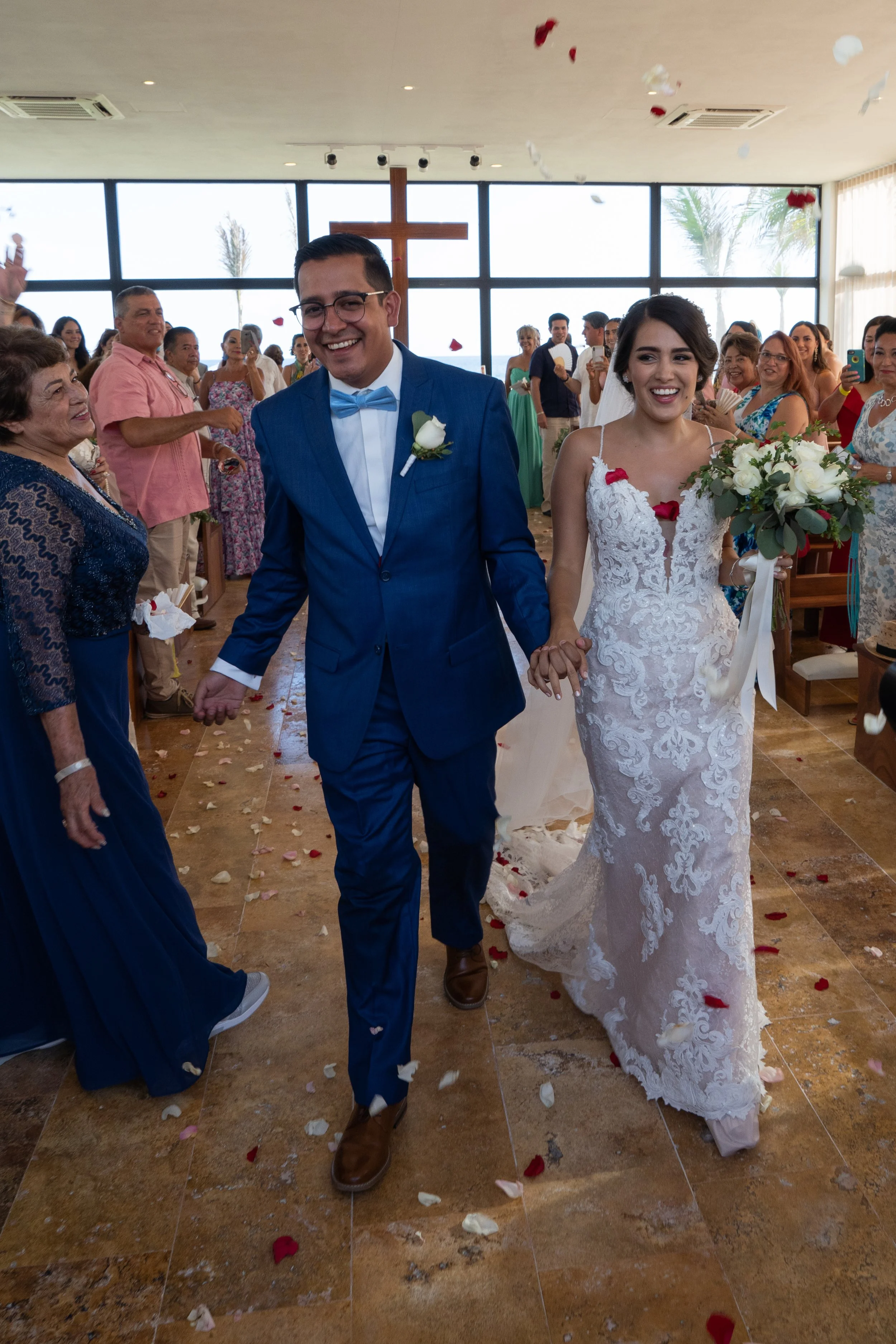 Pareja de novios caminando por la iglesia decorada, rodeados de invitados celebrando su boda.