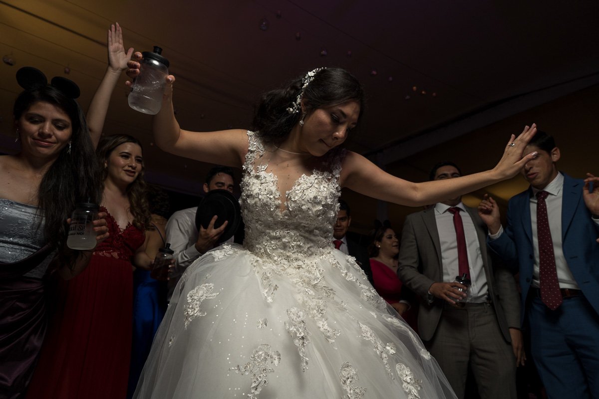 A bride in a white wedding dress dancing at her wedding reception surrounded by guests.