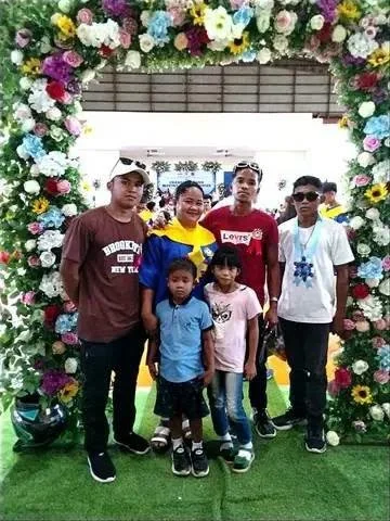 Group of five children standing inside a floral arch at a photo booth.